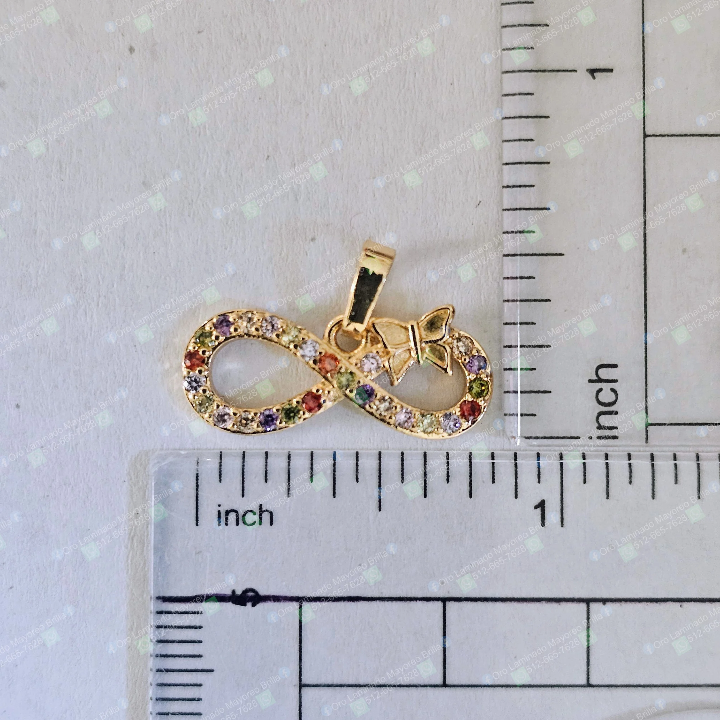Dije infinito con mariposa color oro y piedras decorativas multicolores visibles | Gold color infinity and butterfly pendant with visible multicolor decorative stones