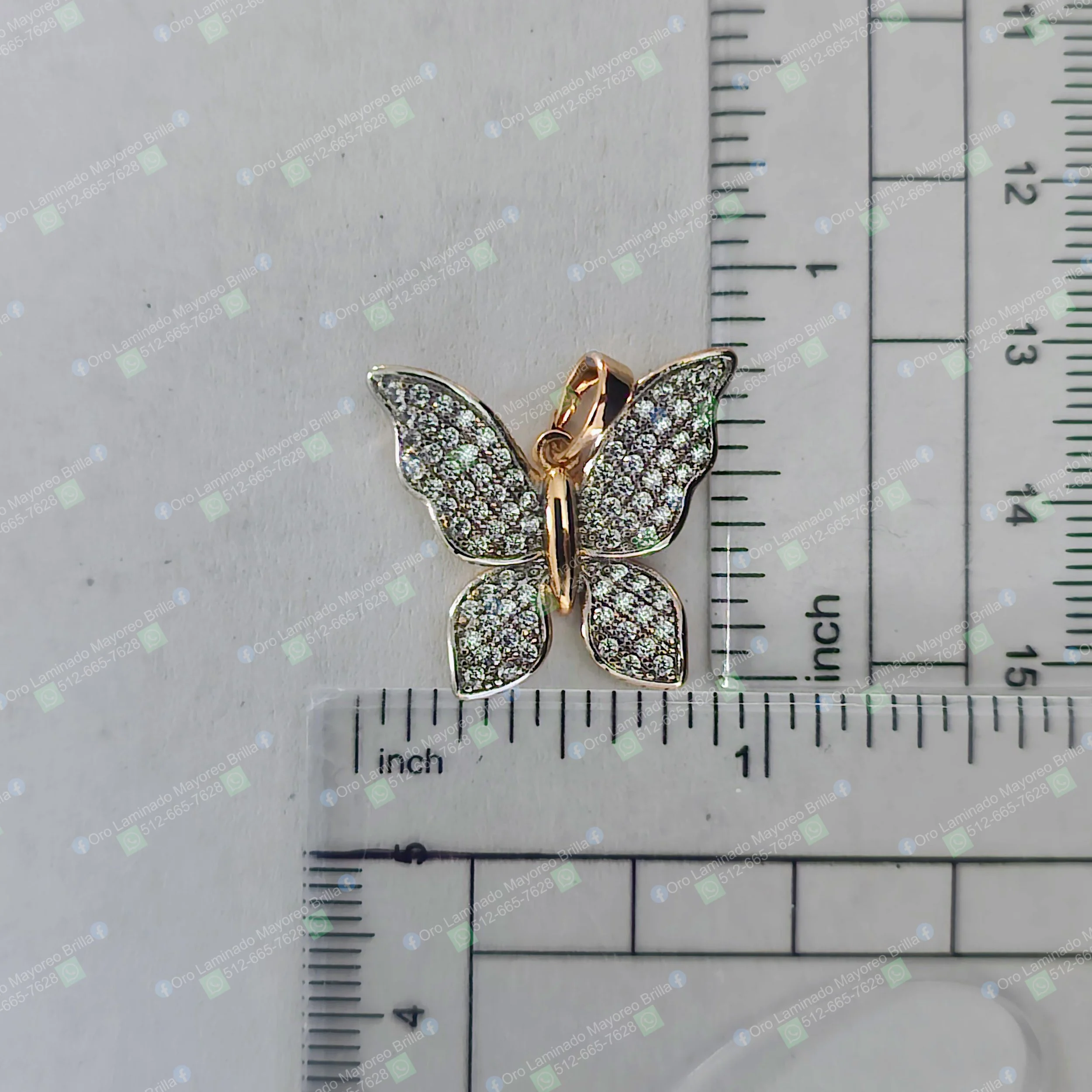 Dije de mariposa color oro con piedras decorativas visibles y diseño detallado | Gold color butterfly pendant with visible decorative stones and detailed design