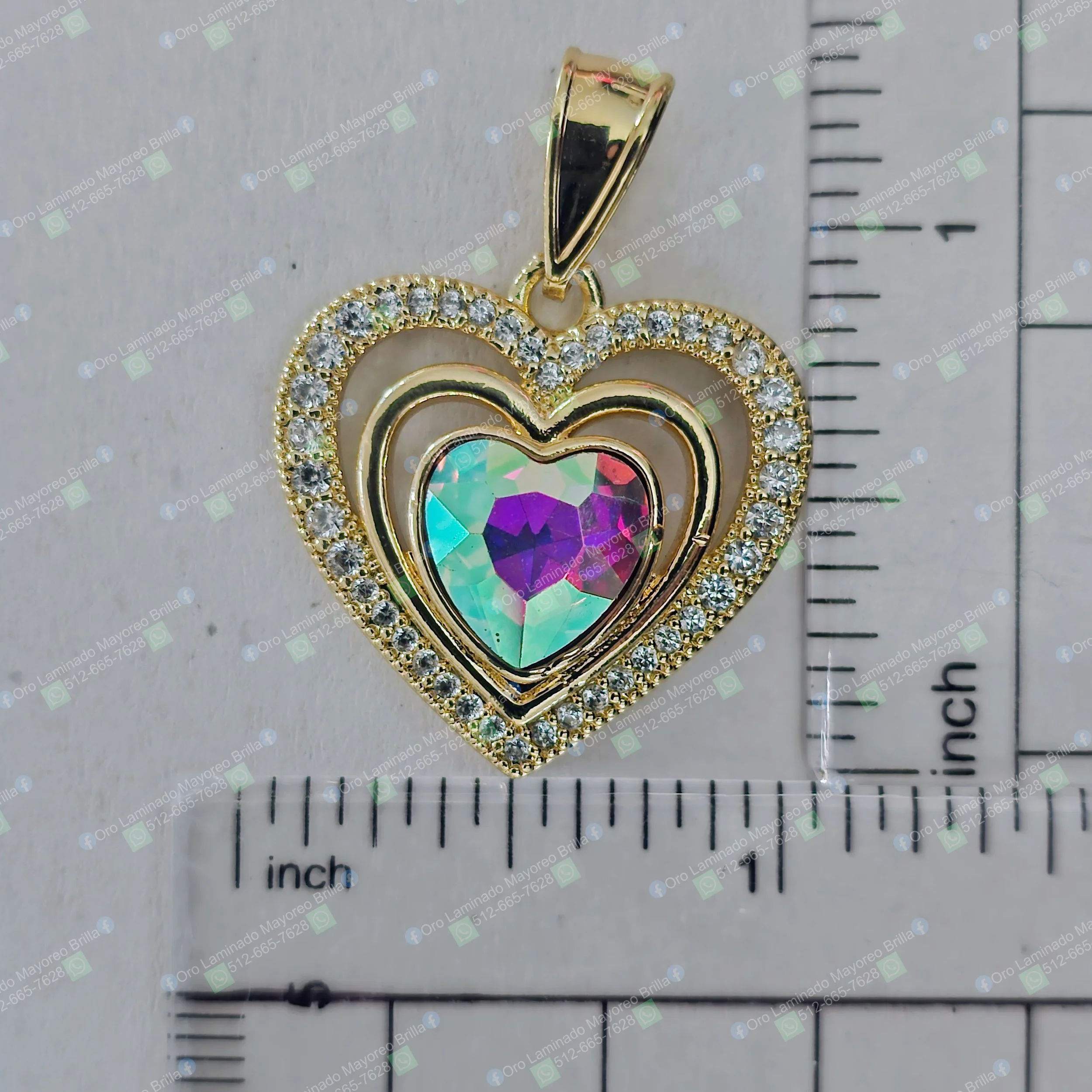 Dije de corazon color oro con piedras decorativas visibles y centro facetado multicolor | Gold color heart pendant with visible decorative stones and faceted multicolor center