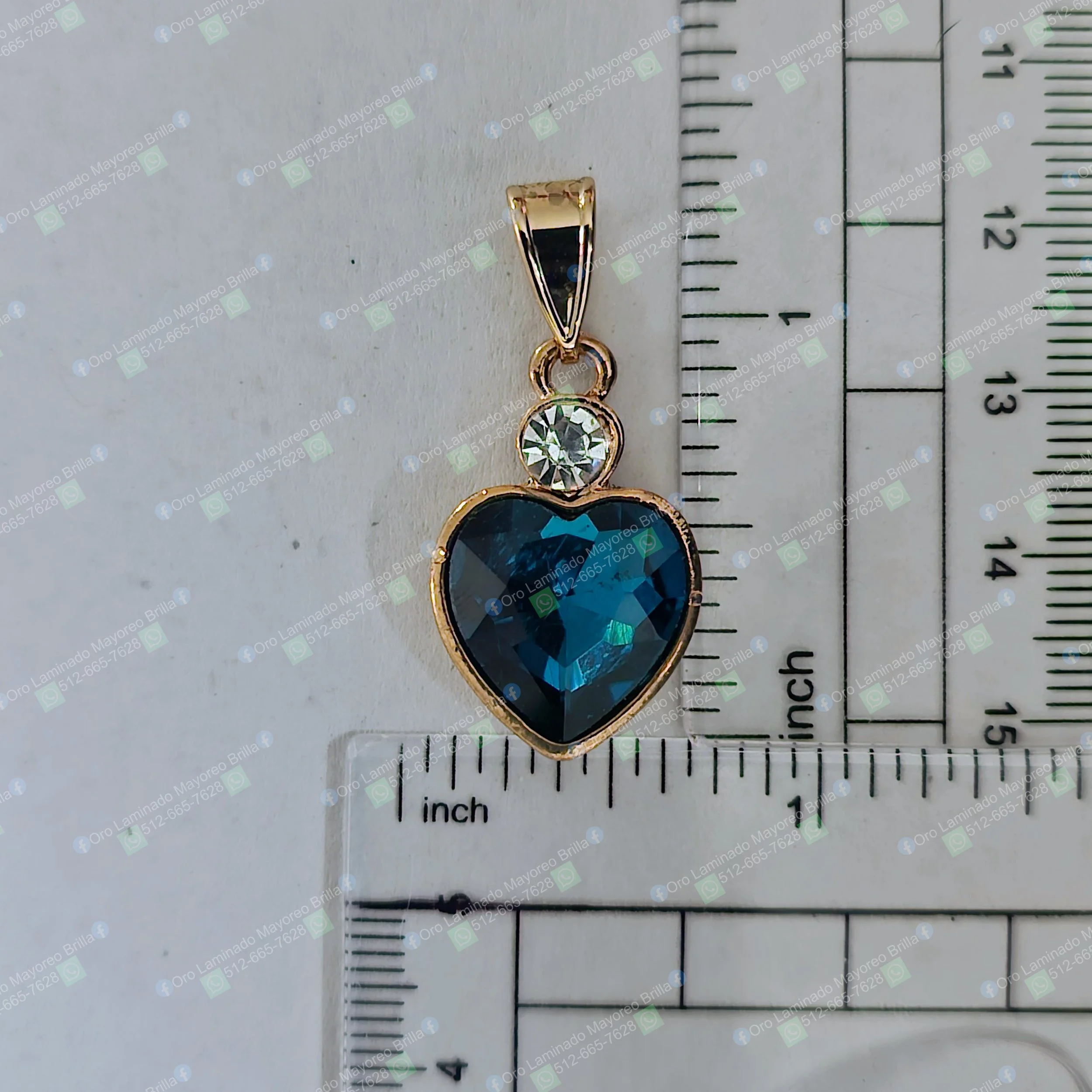 Dije de corazon color oro con piedra azul facetada y piedra clara visible | Gold color heart pendant with faceted blue and visible clear stones