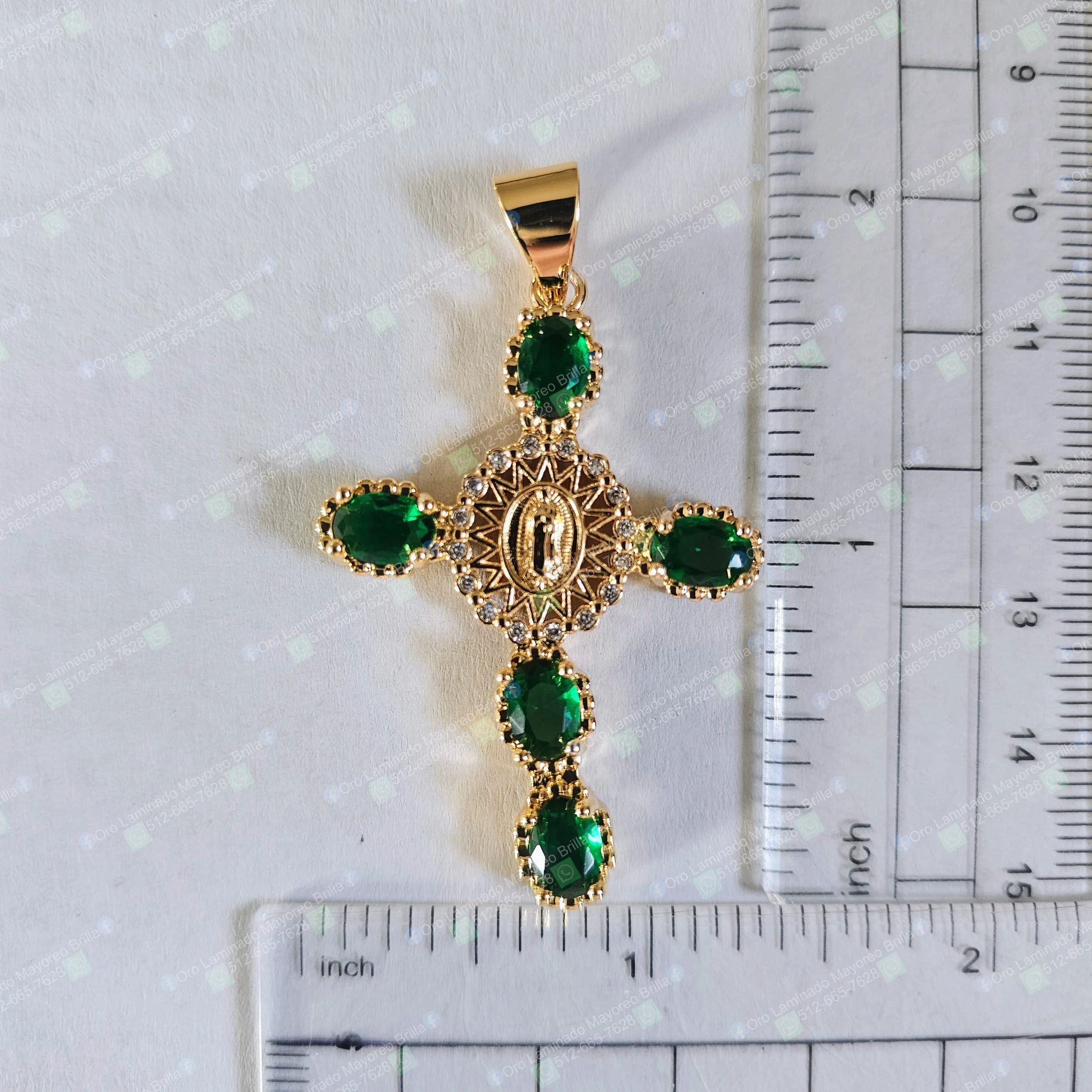 Dije cruz color oro con Virgen en centro y piedras verdes decorativas visibles | Gold color cross pendant with Virgin figure and visible green decorative stones