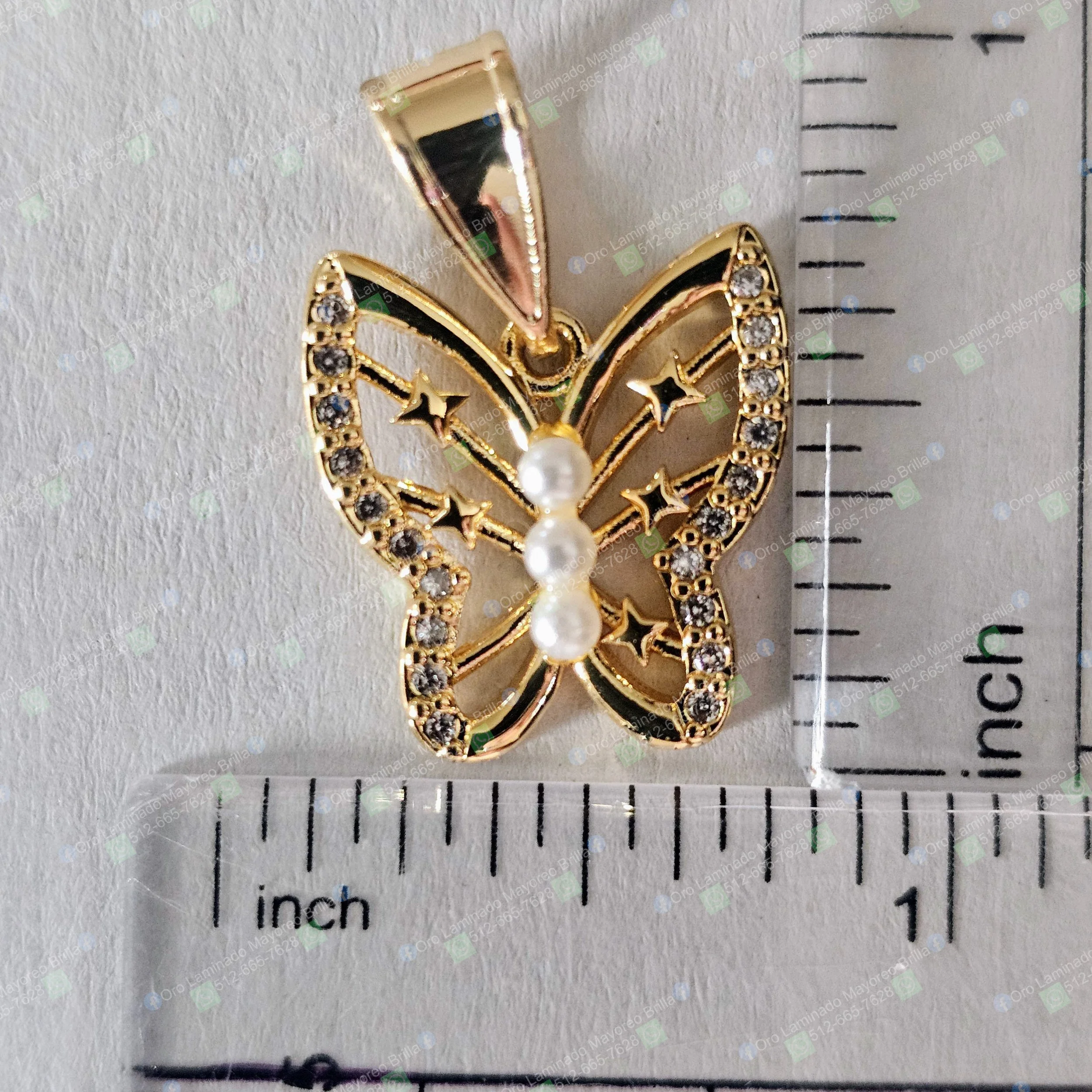 Dije mariposa color oro con perlas artificiales y piedras decorativas visibles | Gold color butterfly pendant with artificial pearls and visible decorative stones