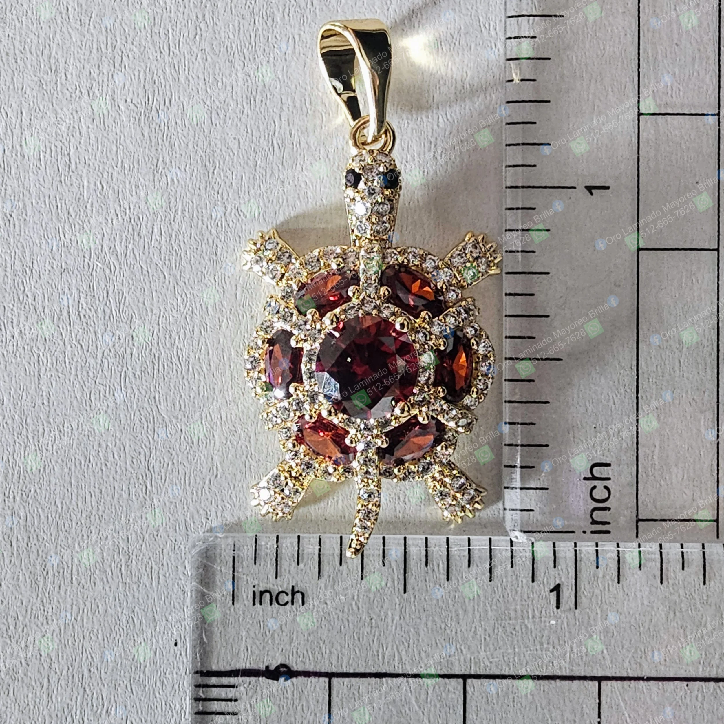 Dije de tortuga color oro con piedras decorativas rojas y cristalinas visibles | Gold color turtle pendant with visible red and clear decorative stones