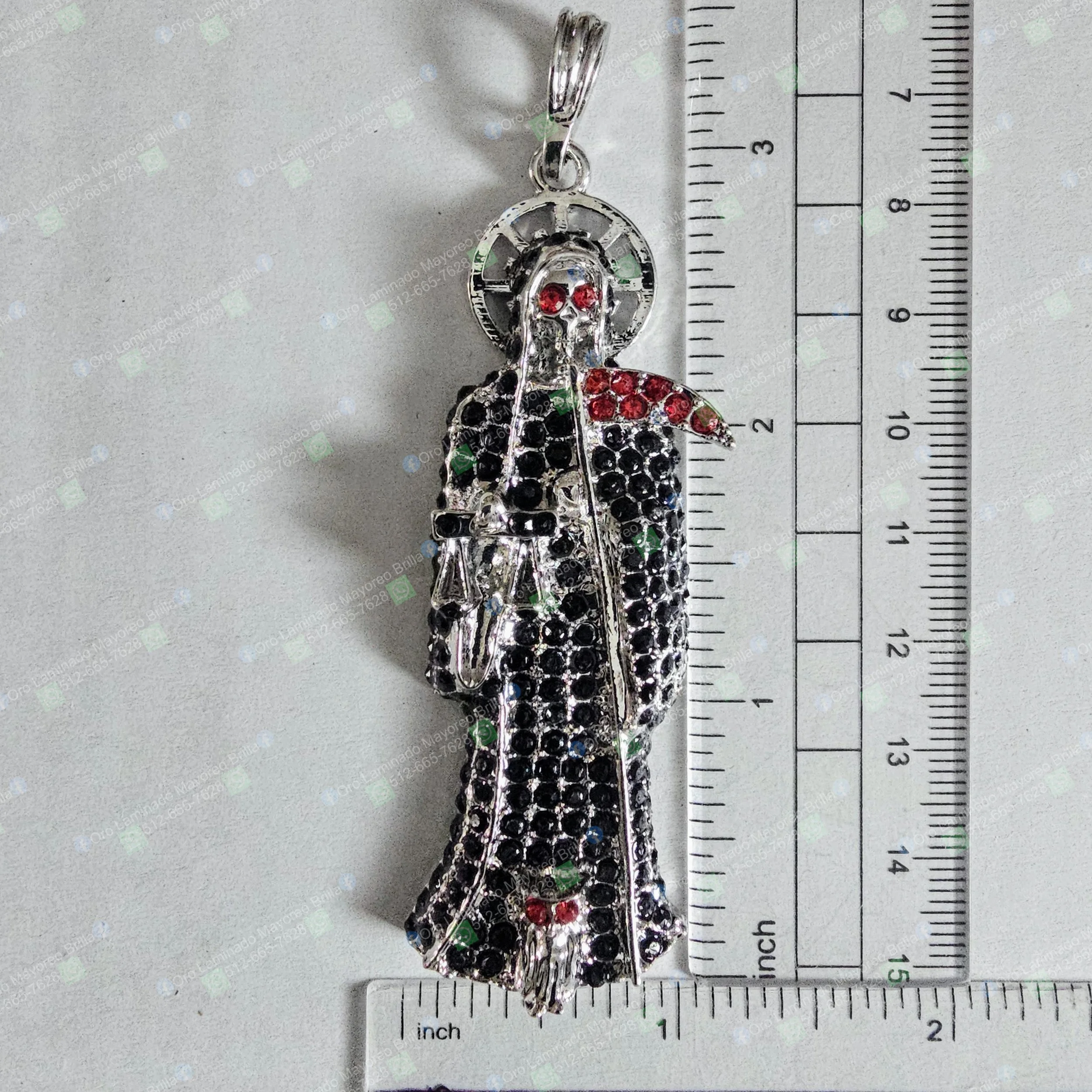 Dije Santa Muerte color plata con piedras decorativas rojas y negras visibles | Silver color Santa Muerte pendant with visible red and black decorative stones
