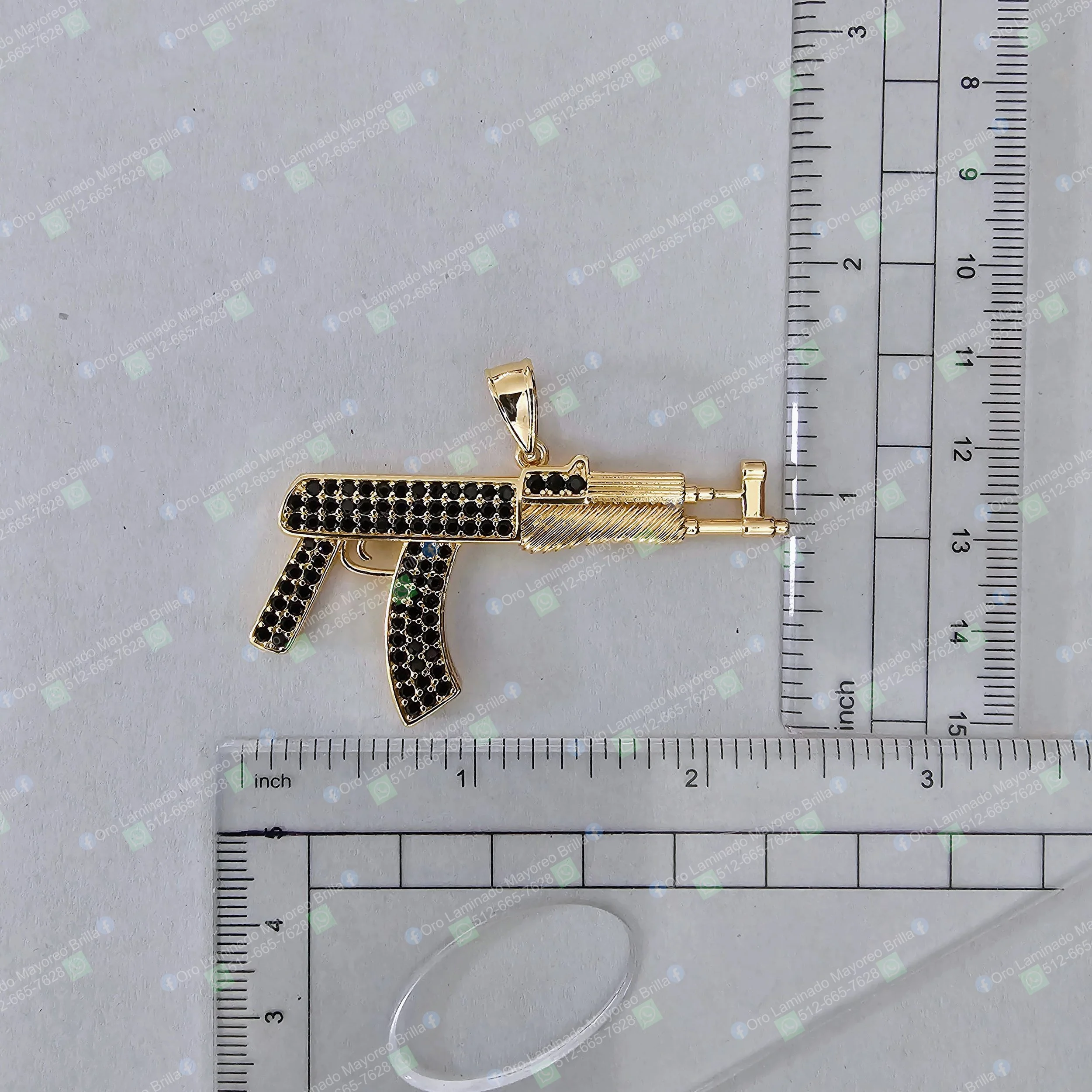 Dije rifle color oro con detalles de piedras negras visibles | Gold color rifle pendant with visible black stone details