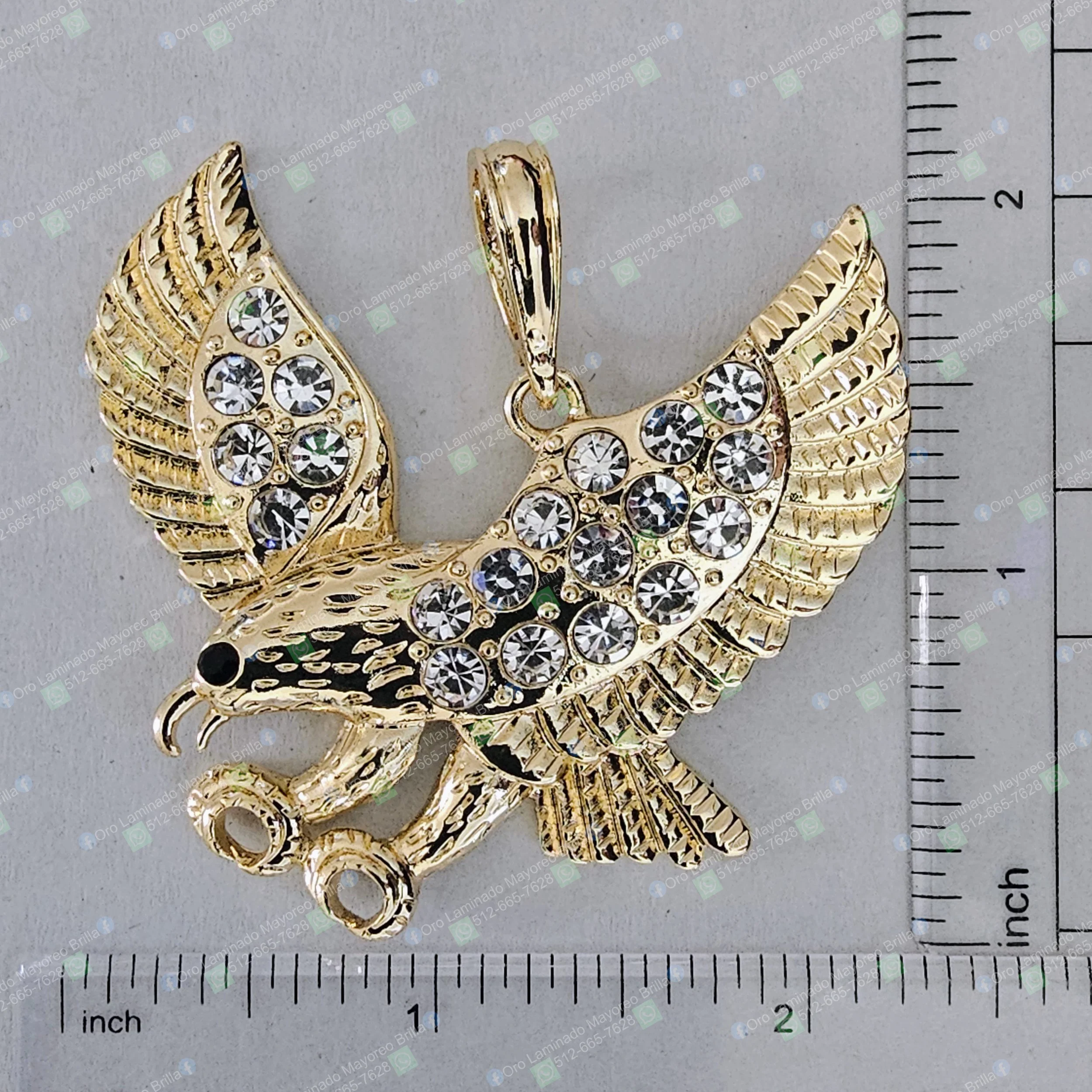 Dije de aguila color oro con piedras decorativas visibles y detalles grabados | Gold color eagle pendant with visible decorative stones and engraved details