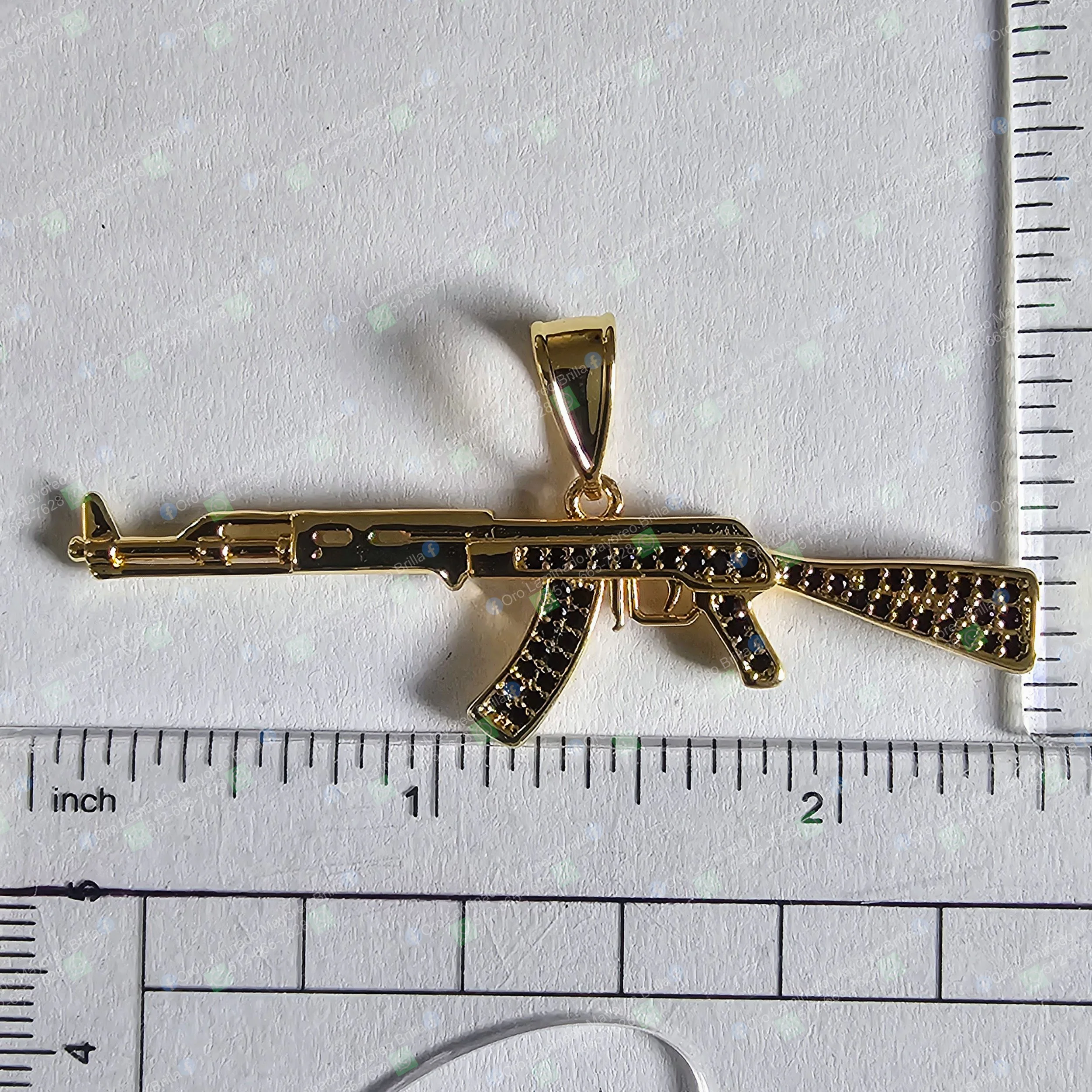 Dije de rifle color oro con piedras negras decorativas visibles | Gold color rifle pendant with visible black decorative stones
