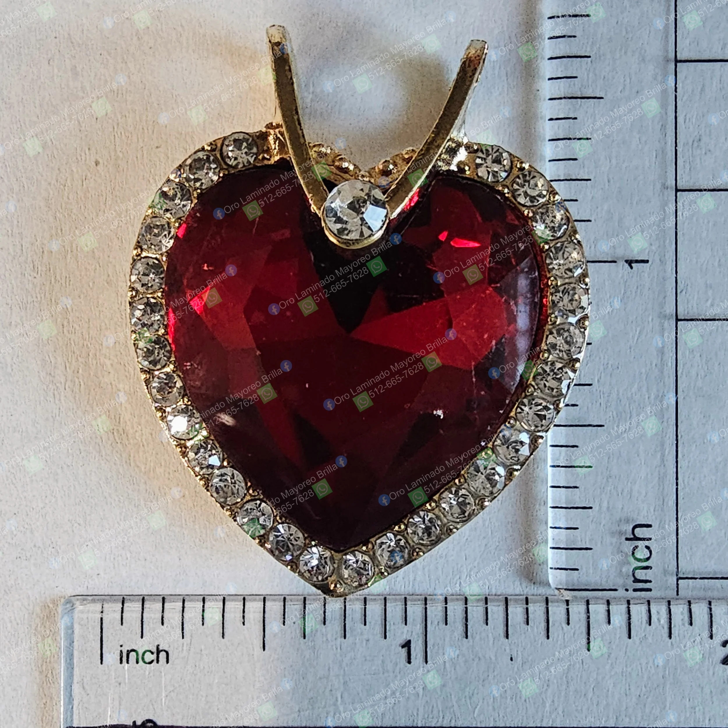 Dije de corazon color oro con piedra roja facetada y piedras brillantes visibles | Gold color heart pendant with faceted red stone and visible bright stones