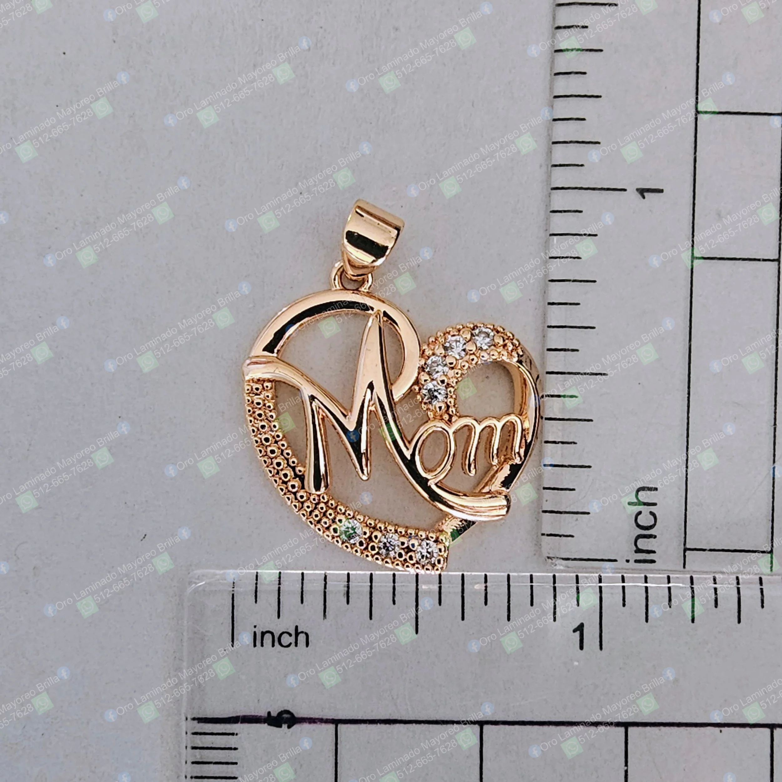Dije de corazon color oro con texto "Mom" y piedras decorativas visibles | Gold color heart pendant with "Mom" text and visible decorative stones