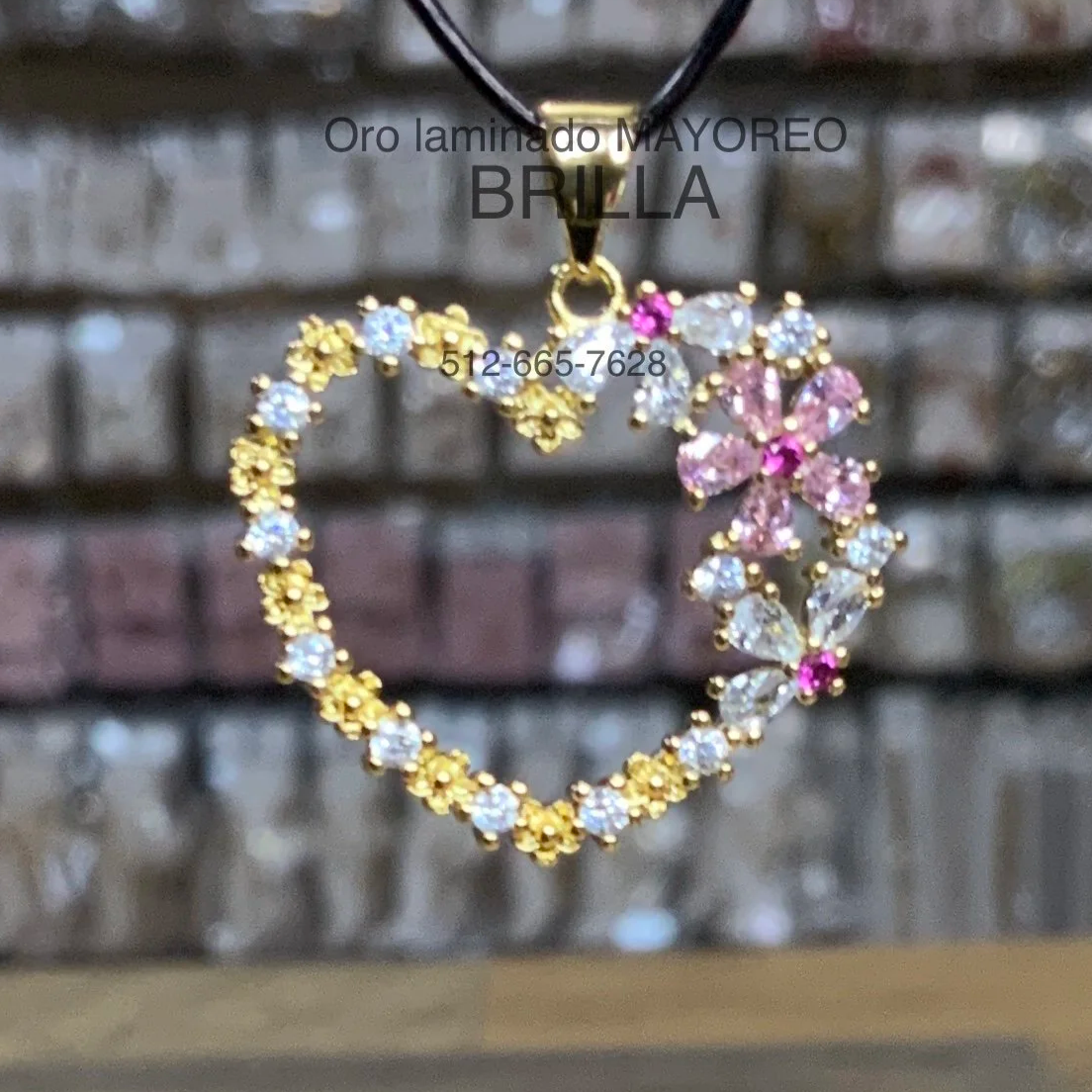 Dije dorado en forma de corazón con flores de zirconias blancas y rosas. Gold heart pendant with pink and white stone flowers.
