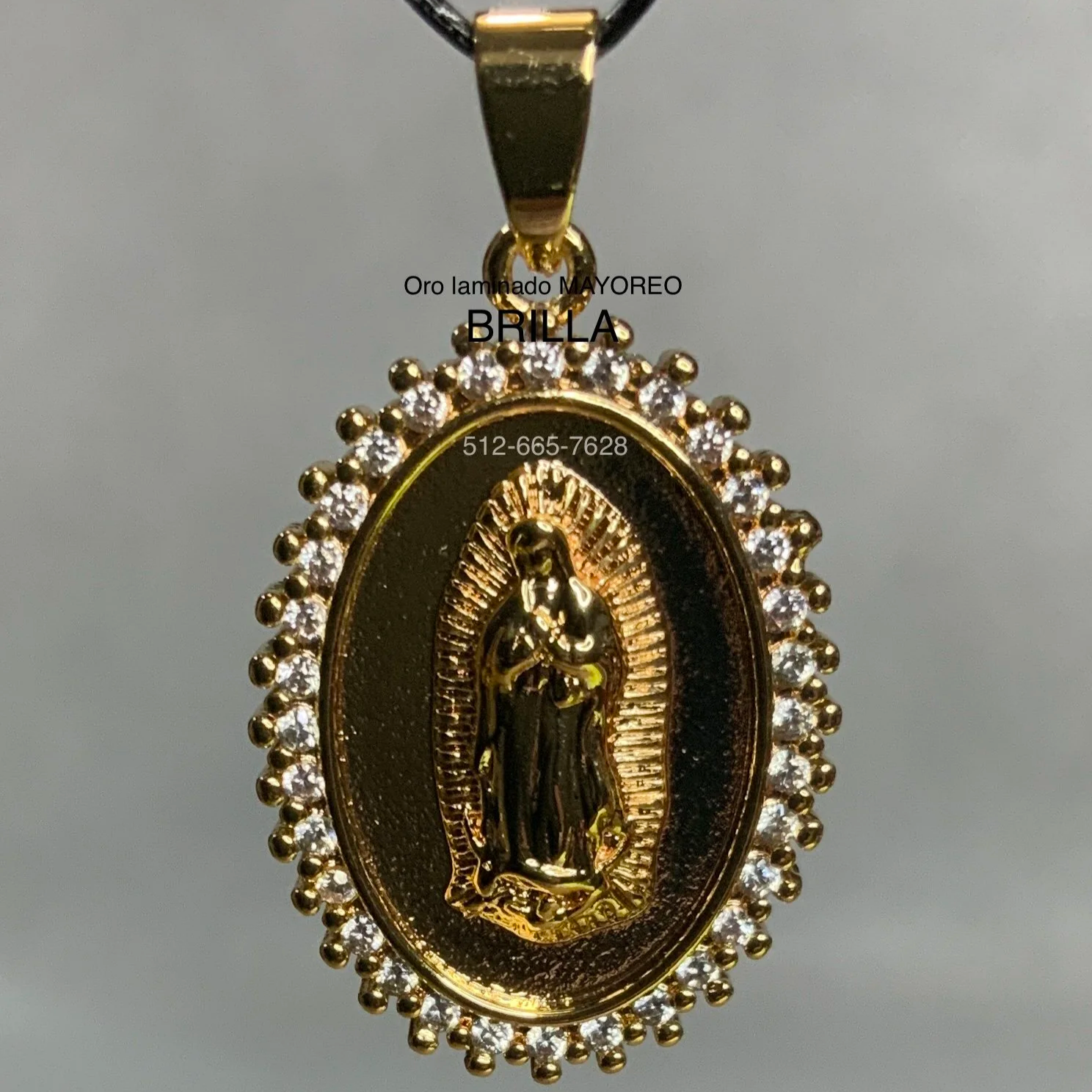 Dije ovalado dorado de la Virgen de Guadalupe con marco de circonias blancas. Gold oval Virgin of Guadalupe pendant with white zircon border.