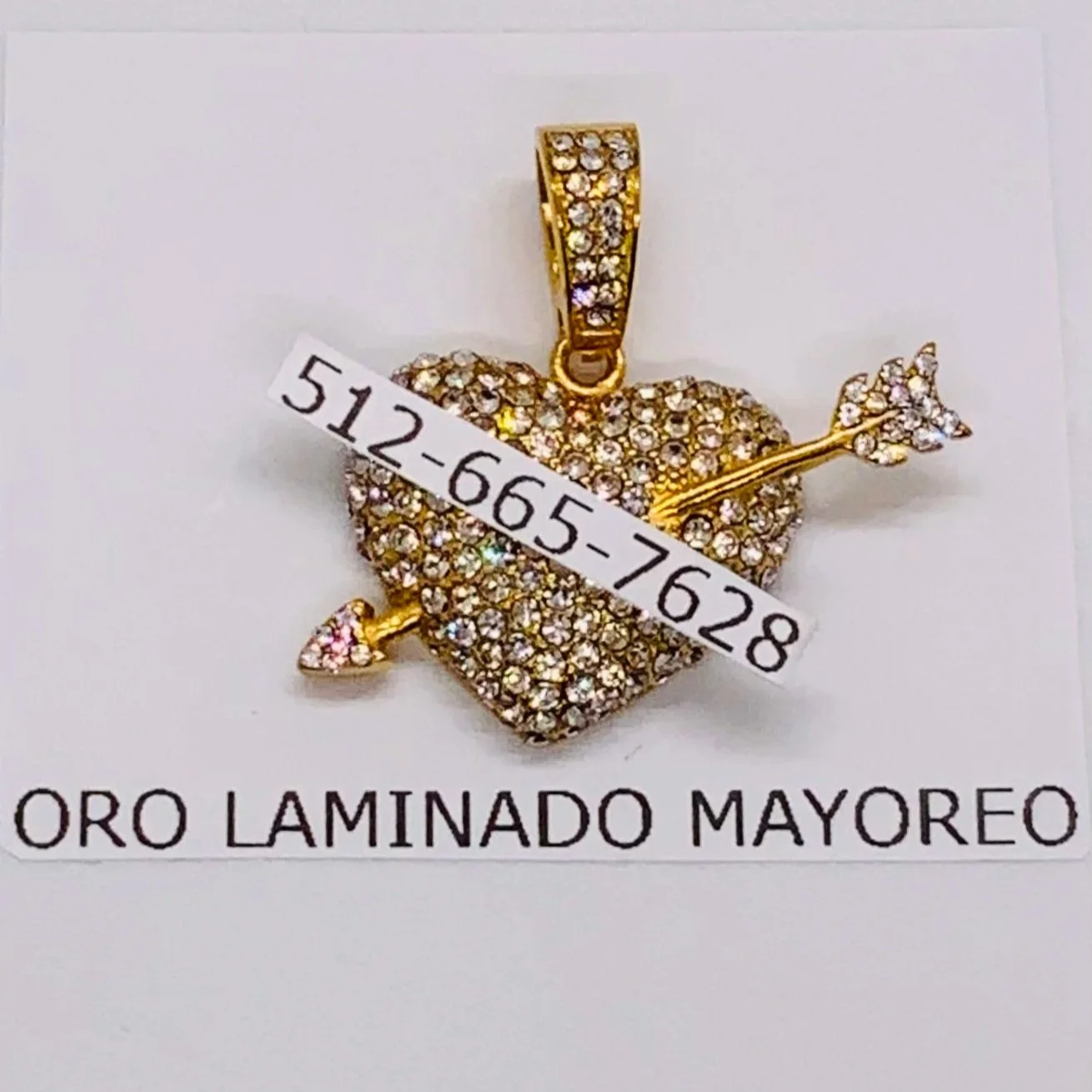 Dije dorado de corazón con flecha incrustada. Gold-tone heart pendant with arrow and rhinestones.