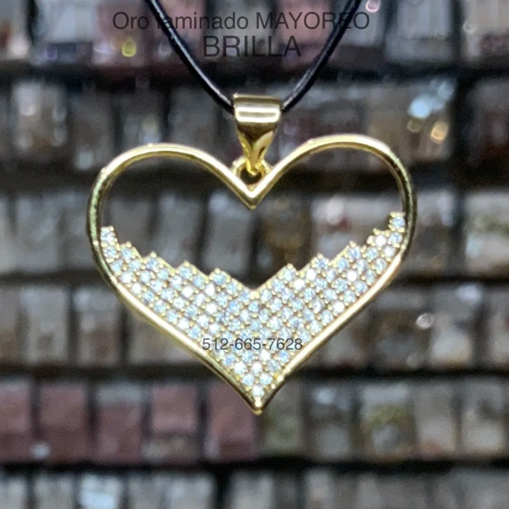 Dije de corazón dorado abierto con parte inferior decorada con piedras blancas en patrón escalonado. Gold heart outline pendant with lower section covered in clear stones.