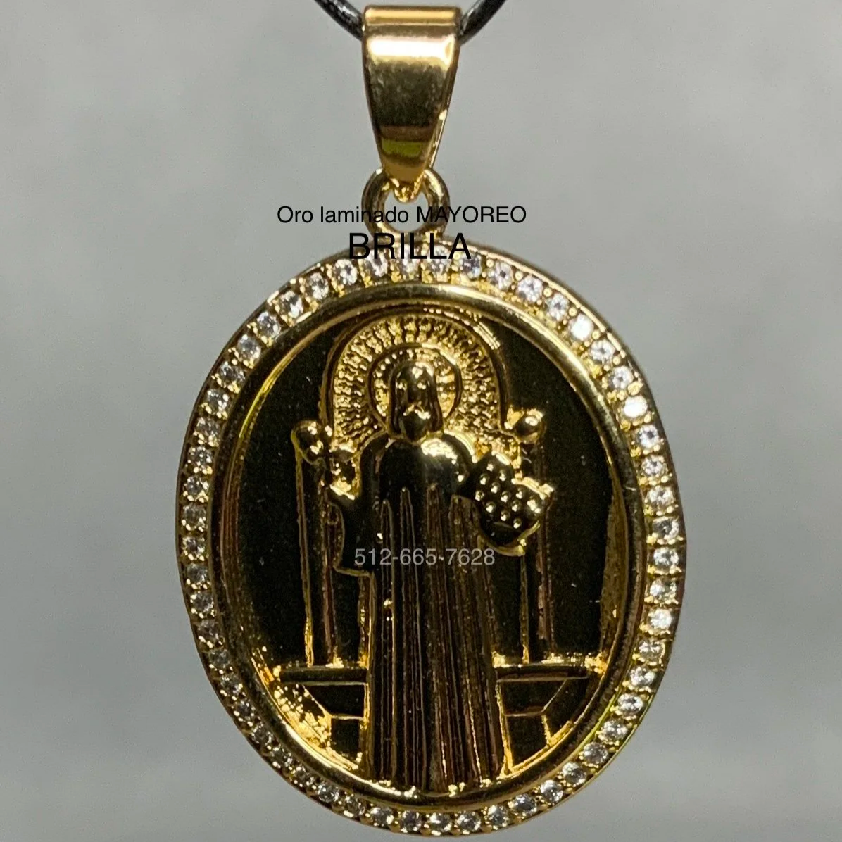 Dije ovalado dorado de San Judas Tadeo con borde de piedras brillantes, imagen religiosa grabada. Saint Jude gold pendant with stone border and engraved figure.