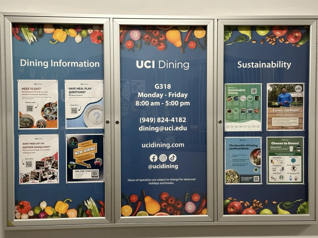 Three blue informational posters about UCI Dining, featuring images of vegetables and fruits at the top and bottom, with details about dining hours, sustainability, and events
