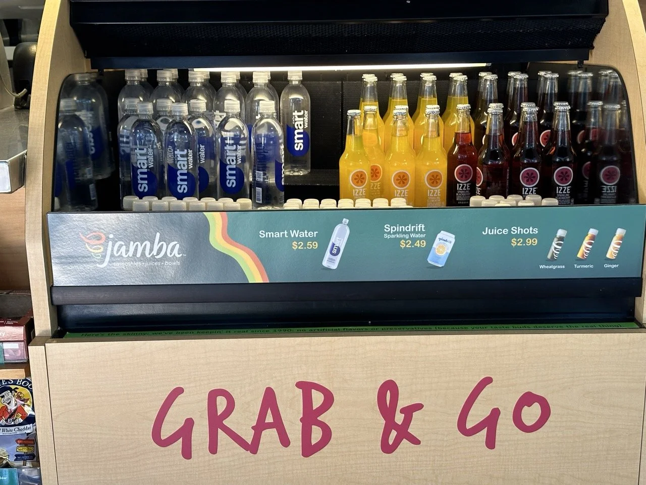 A display case with bottled drinks, including Smart Water, Izze Sparkling Water, and Izze Juice Shots, with a sign at the front that says 'GRAB & GO'.