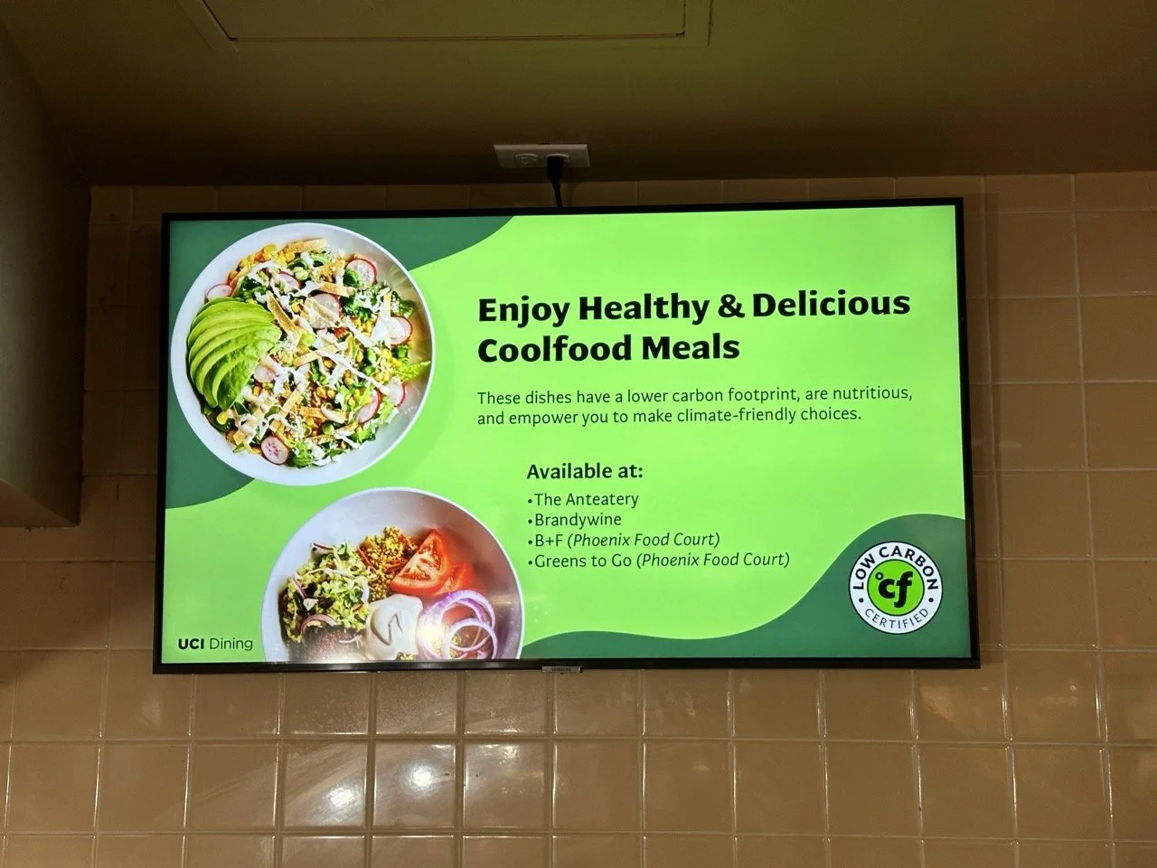 Digital sign promoting healthy and environmentally friendly cool food meals with images of salad bowls featuring vegetables like avocado, radish, tomato, onion, and greens.