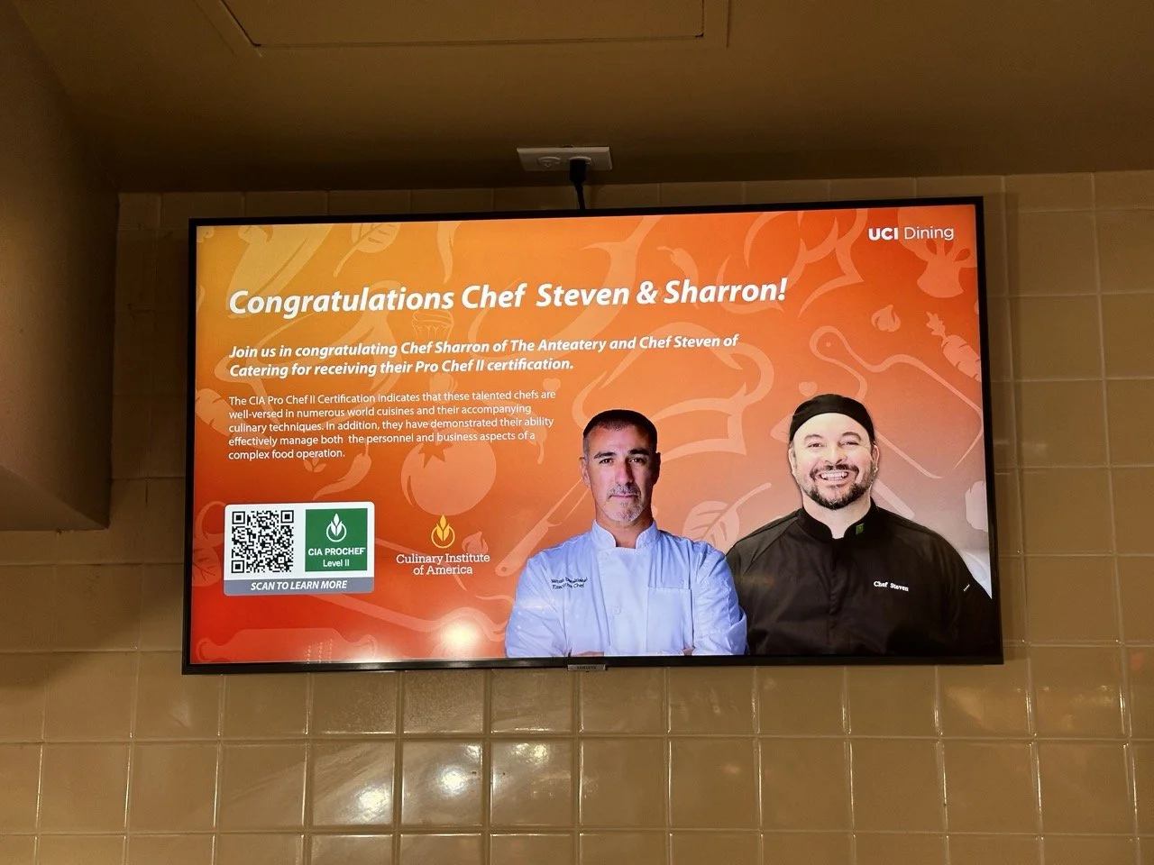 Digital poster with orange background congratulating Chef Steven and Sharron for their culinary achievements, featuring photos of two chefs, a QR code, and logos for CIA ProChef Level 1 and the Culinary Institute of America.