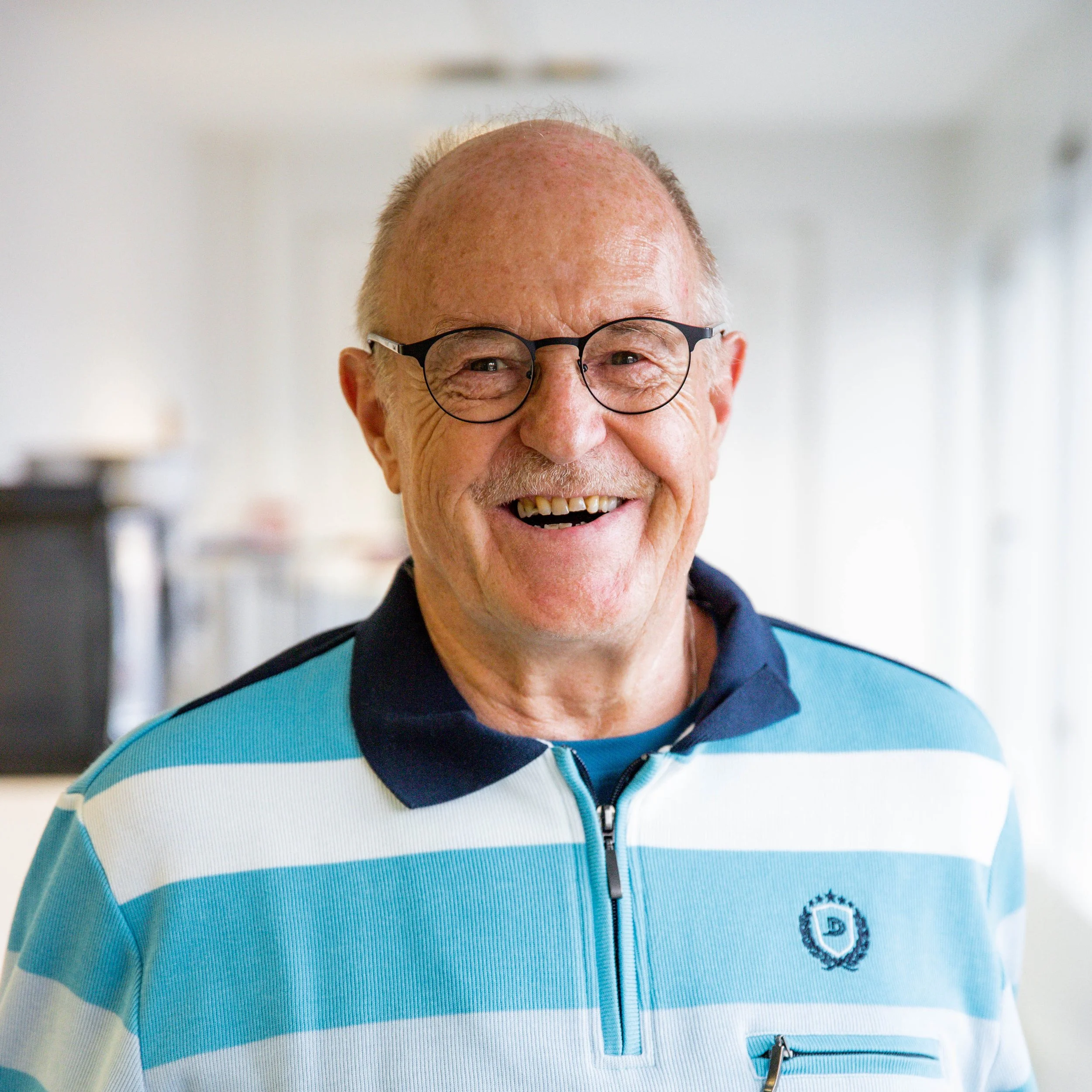 Lächelnder älterer Mann mit Brille in einem hellen Raum