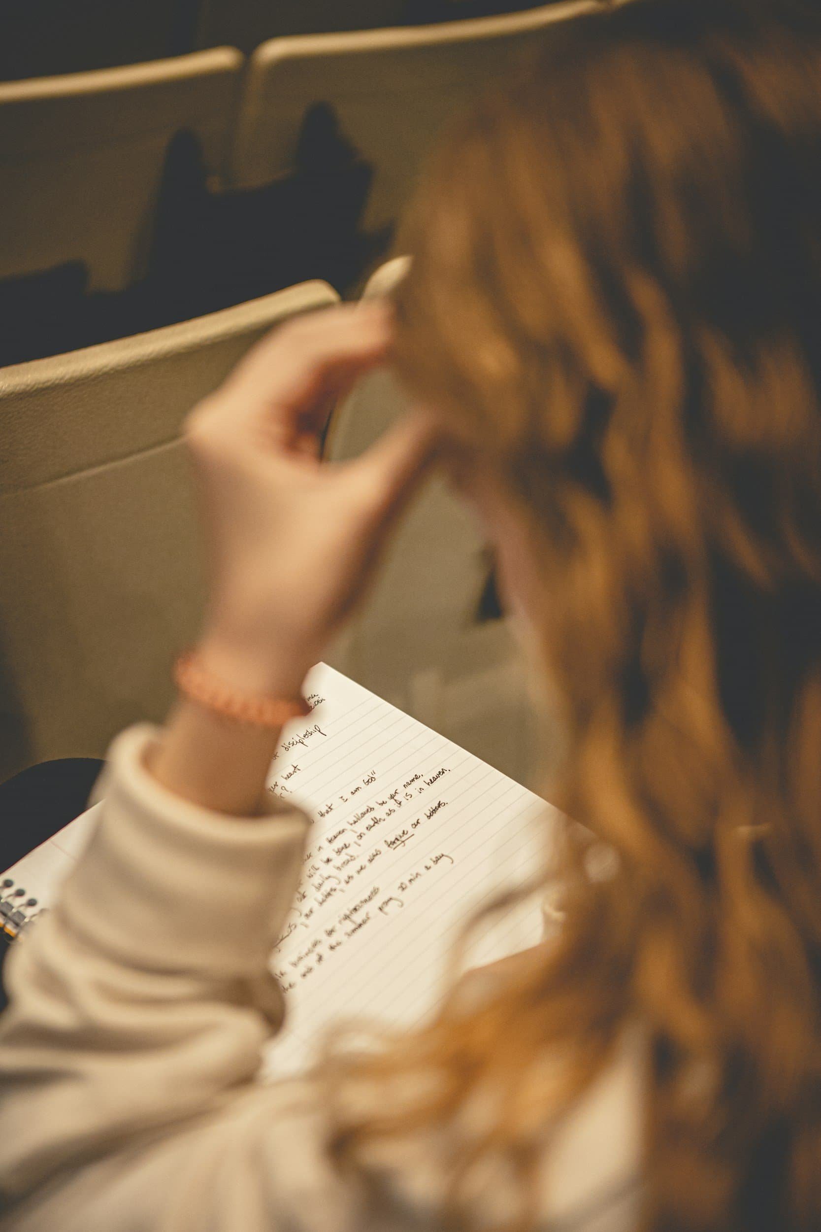 close up of rear of brunette lady hair, reading a notebook