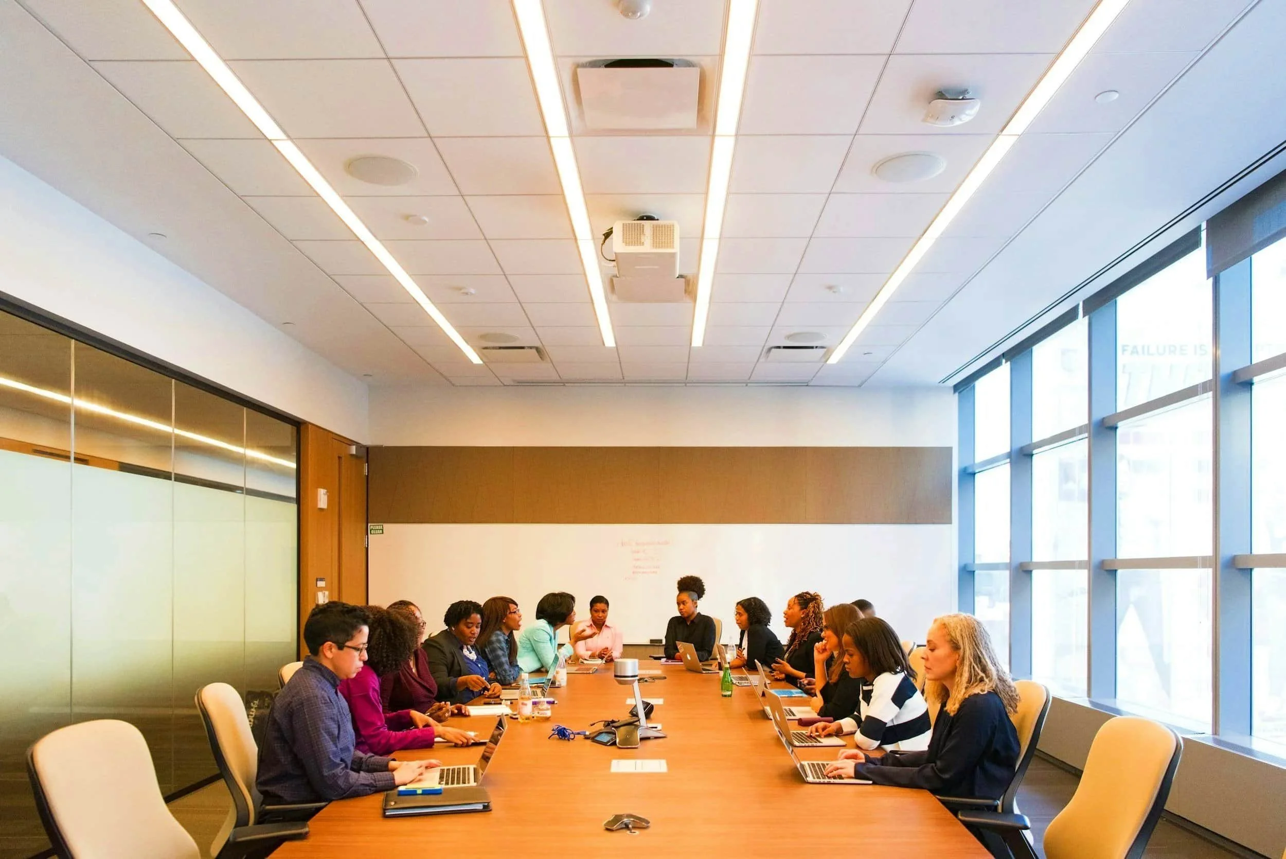Diverse employees sitting round a brightly lit conference table
