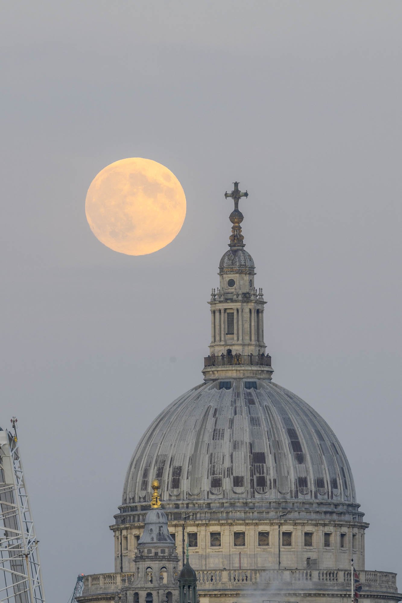 Full moon rising towards the dome of St Pauls cathedral in London.