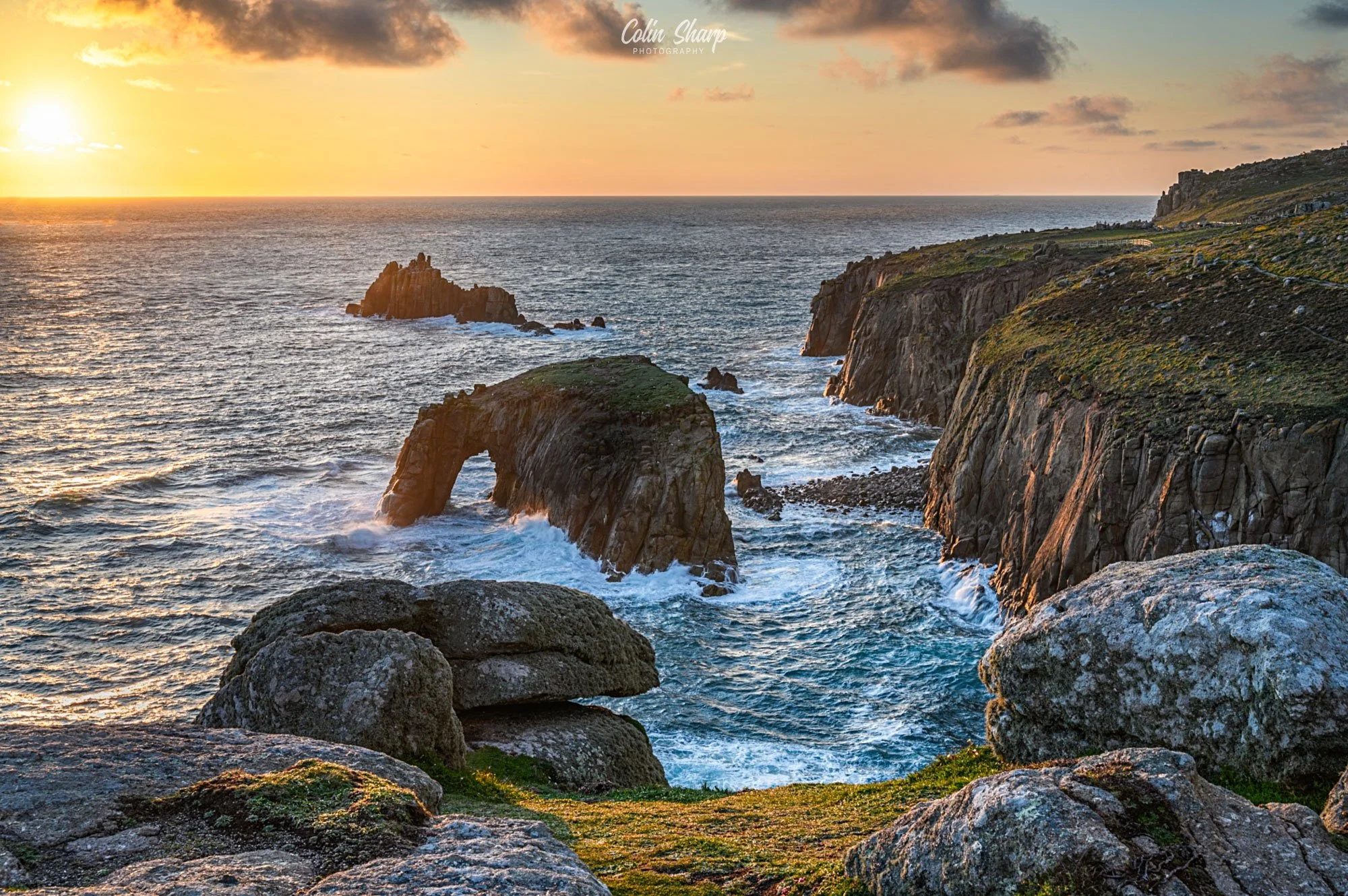Sunset over Enys Dodnan Point at Lands End with the warm light highlighting the relief and textures in the rocks and cliffs