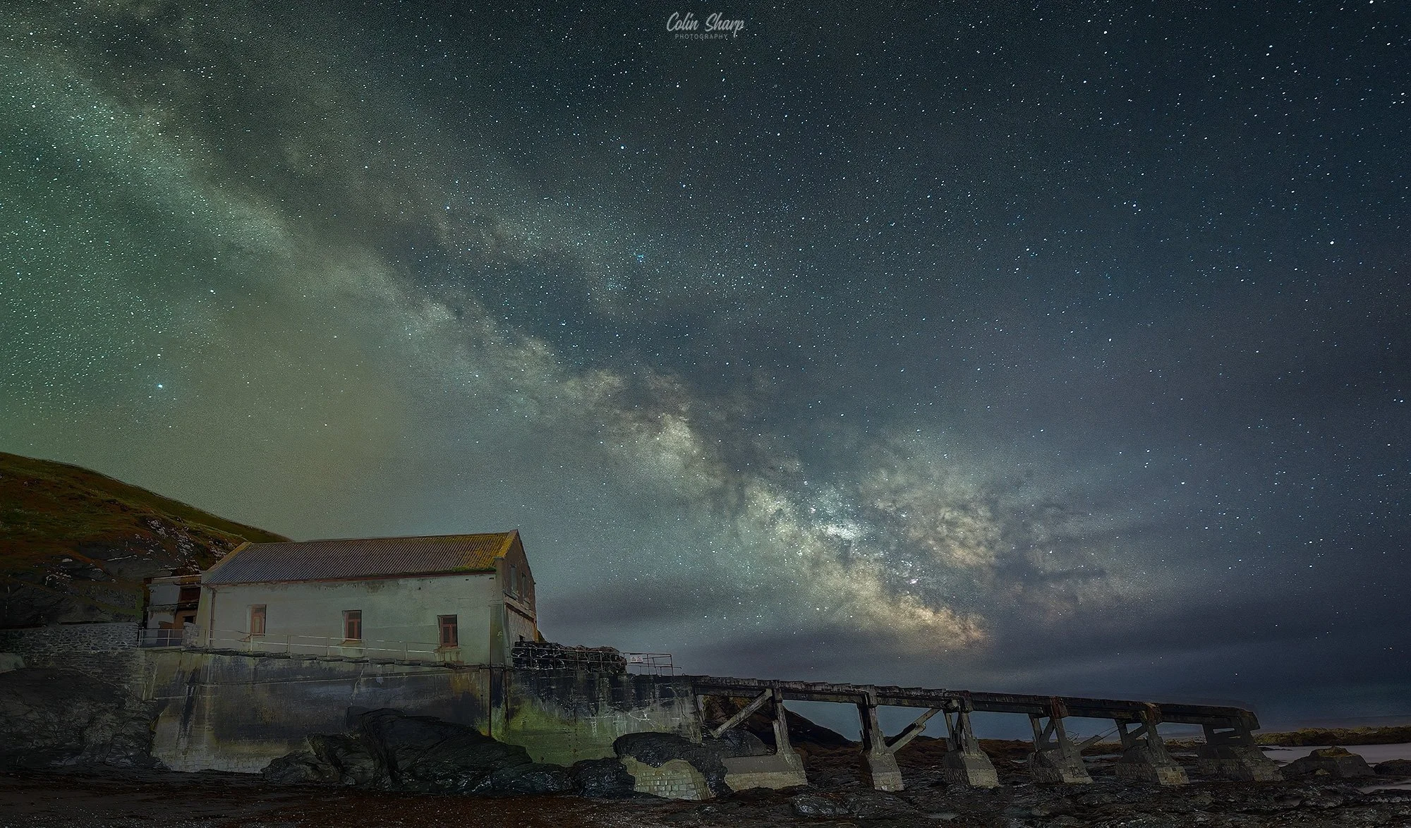 A night sky filled with stars and the Milky Way galaxy above the disued Lifeboat Station at The Lizard in Cornwall.