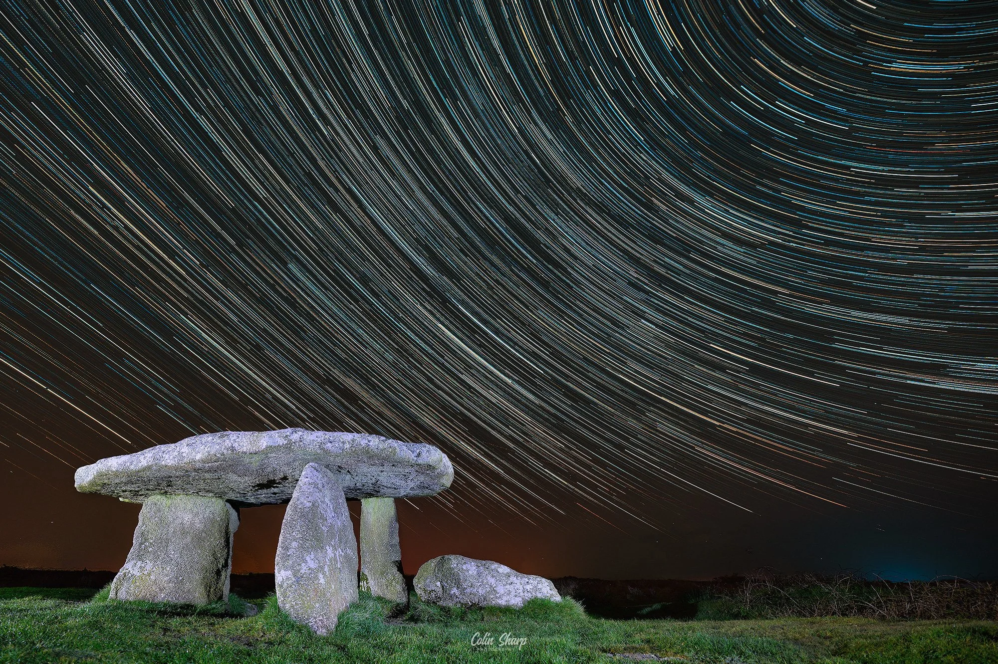 A star trails image at Lanyon Quoit a composite of over 100 night sky images  combined with a light painted foreground.long-exposure photograph of Starstreaks overhead with a stone structure in the foreground.