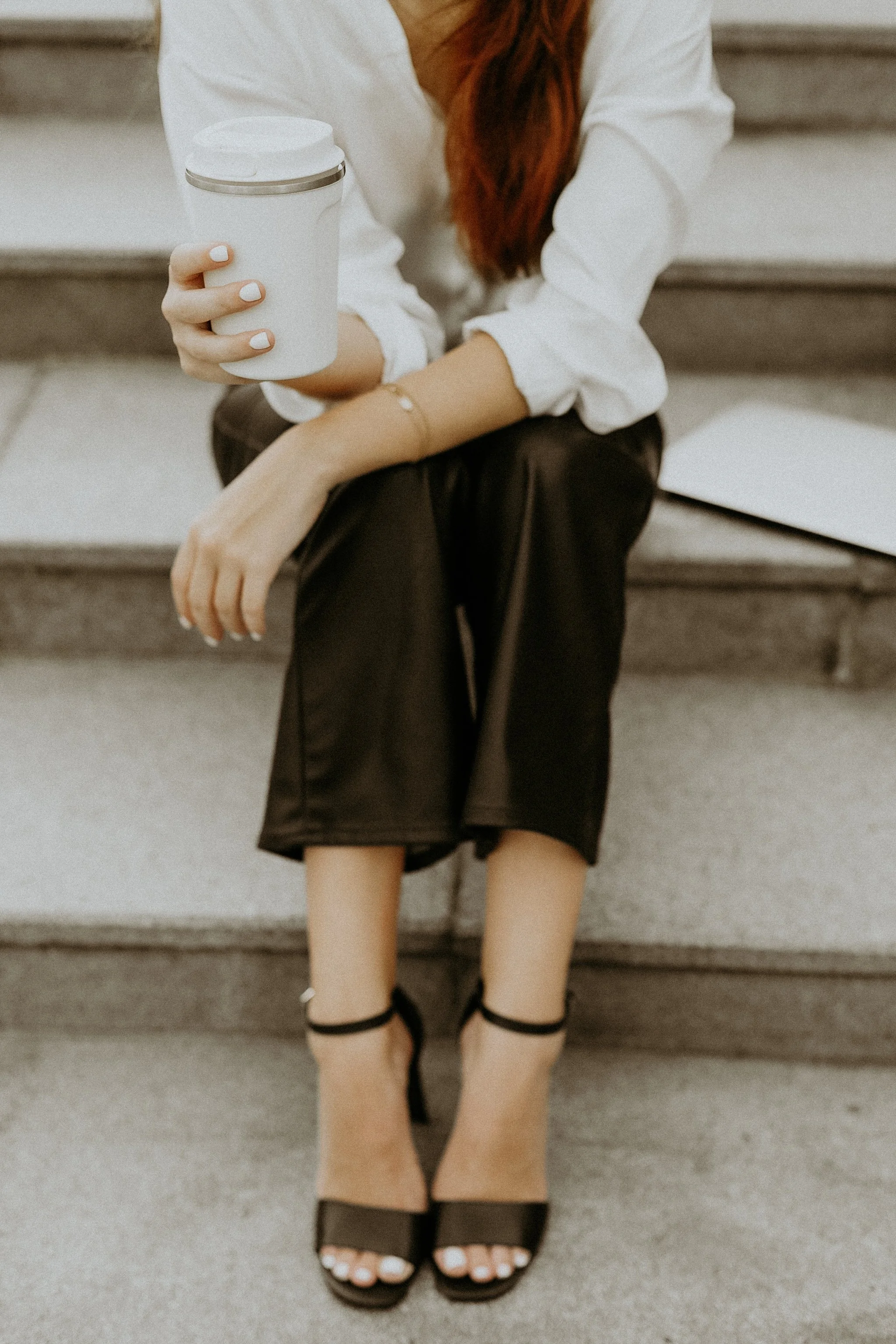 Brandi Lilley of Luneer Mgmt sitting on stairs with a coffee in hand