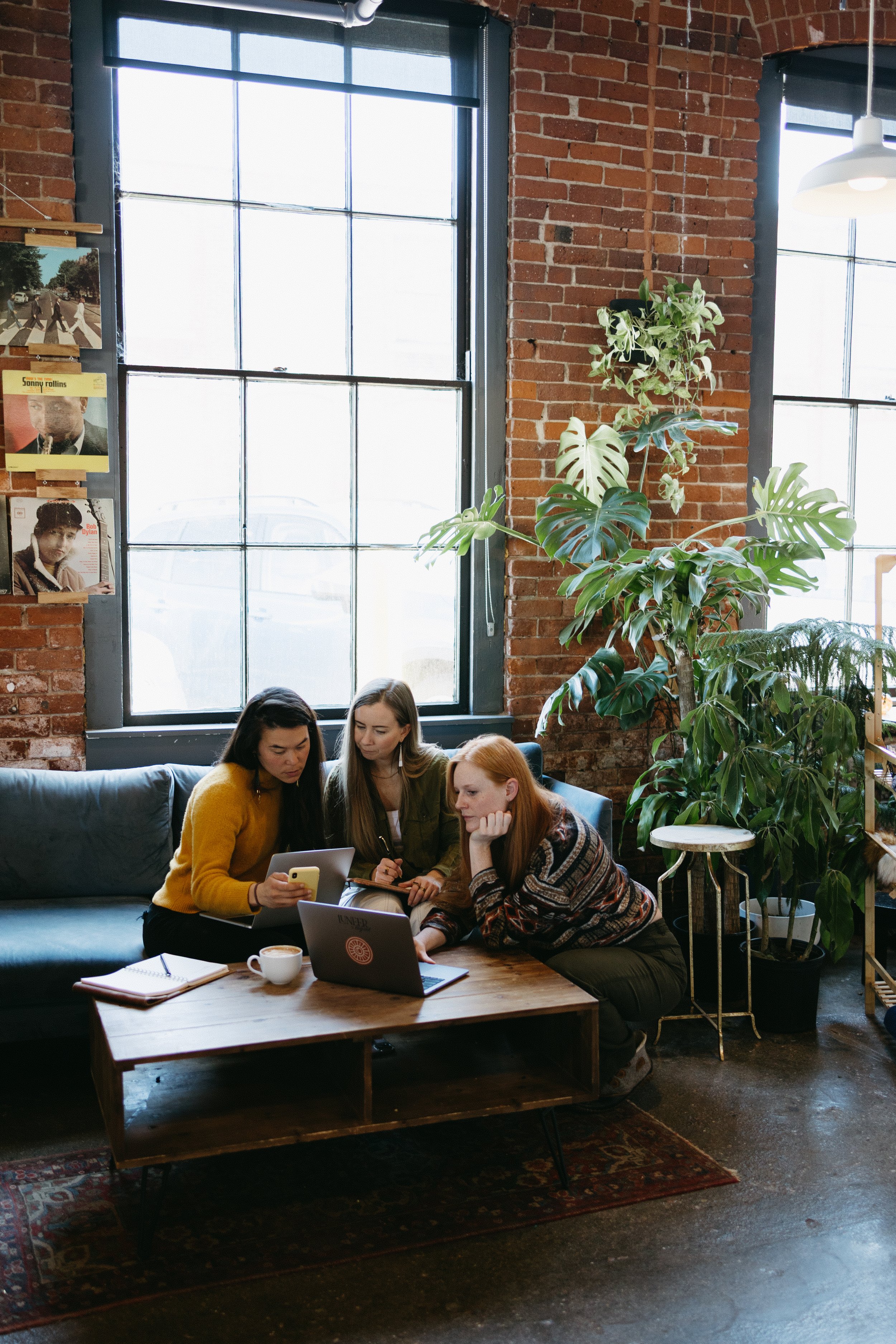 Three colleagues sitting together in a cozy office, reviewing small business SEO strategy on laptop and tablet