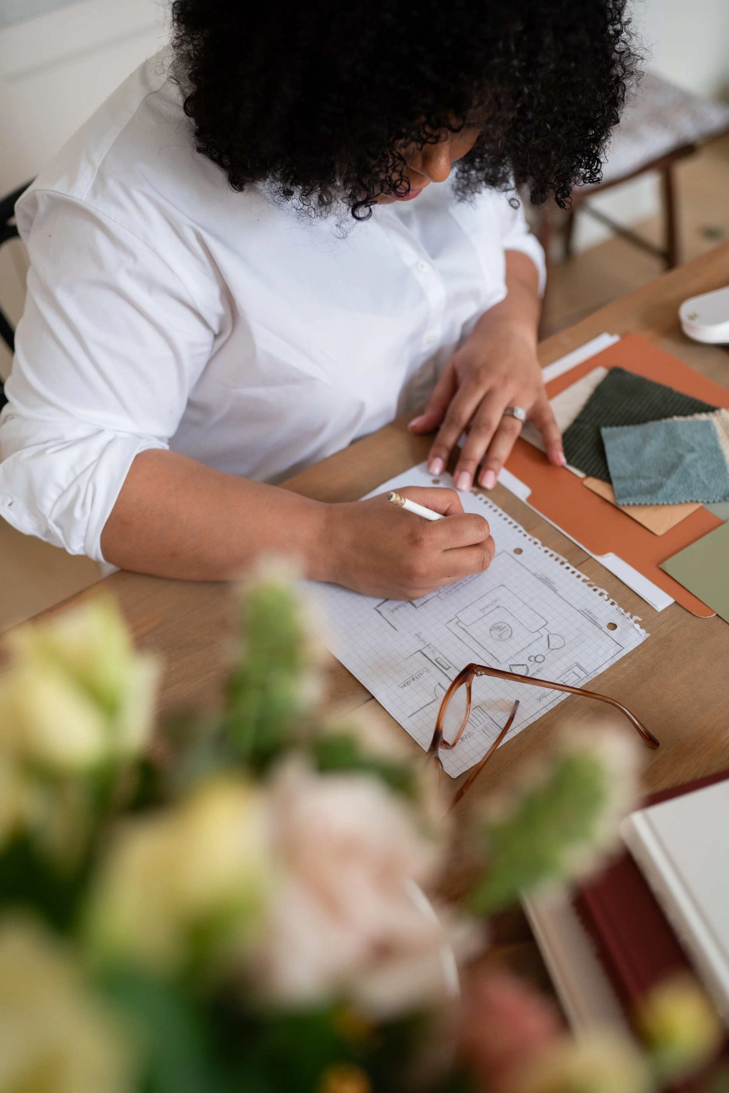 A woman sitting at her desk working on an interior design sketch.