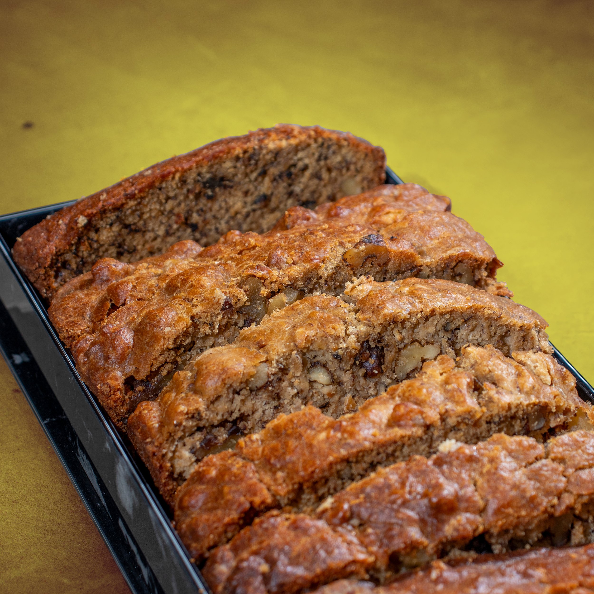 Homemade banana walnut olive oil loaf at 787 coffee with yellow background