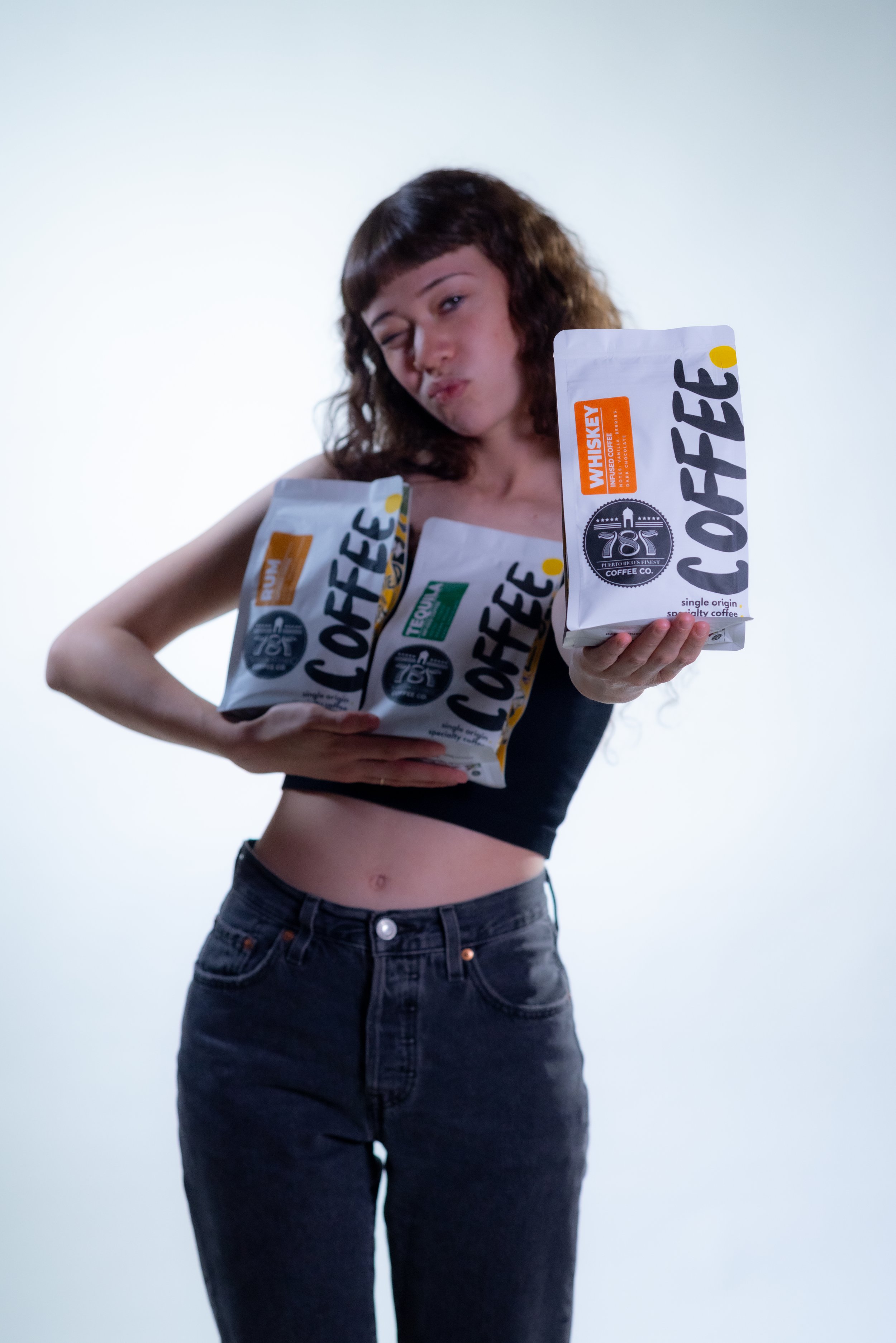 Girl holding the three infused coffee beans by 787 Coffee with the whiskey coffee bag at front
