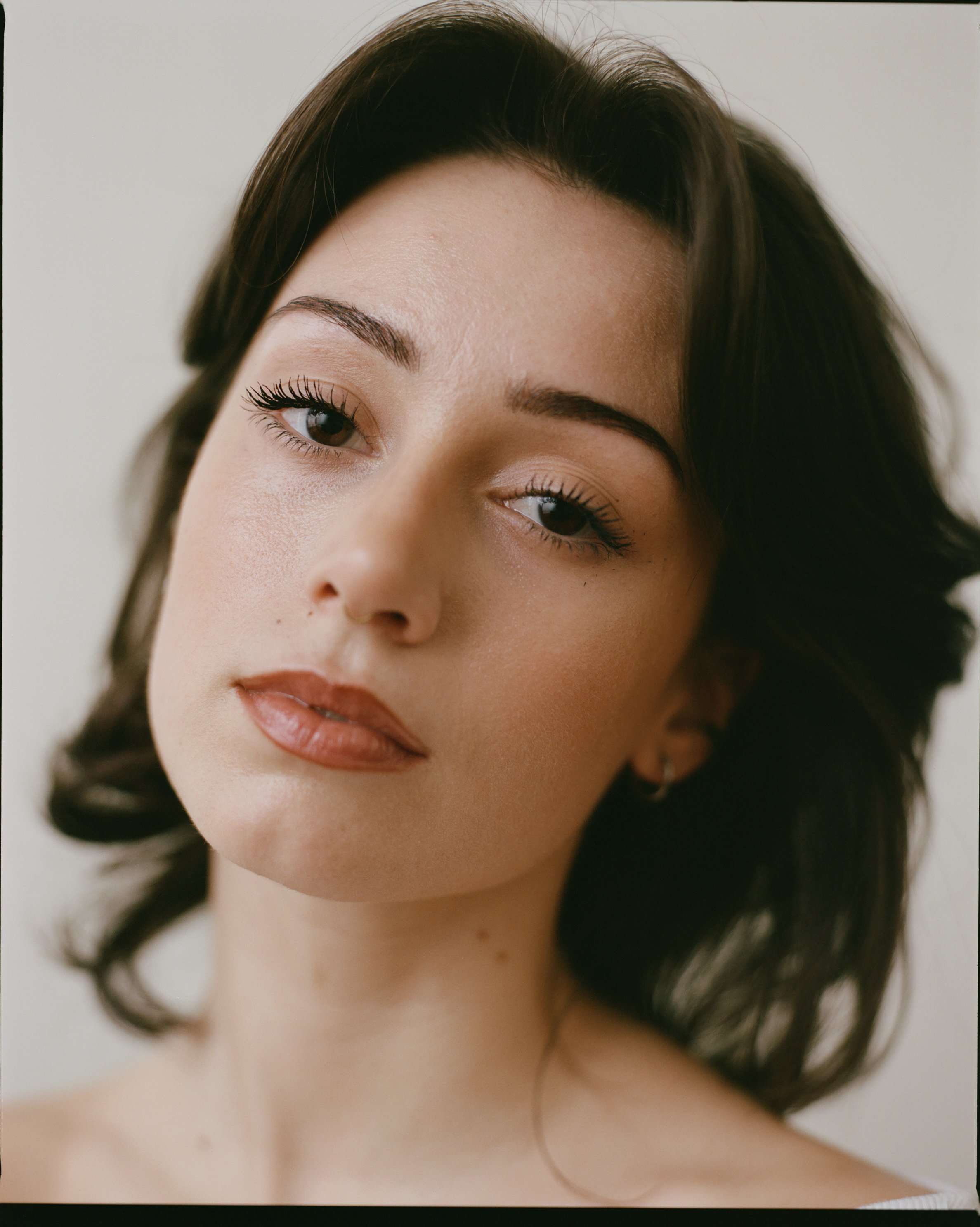 Close-up portrait of a young woman with dark hair, makeup, and light skin.