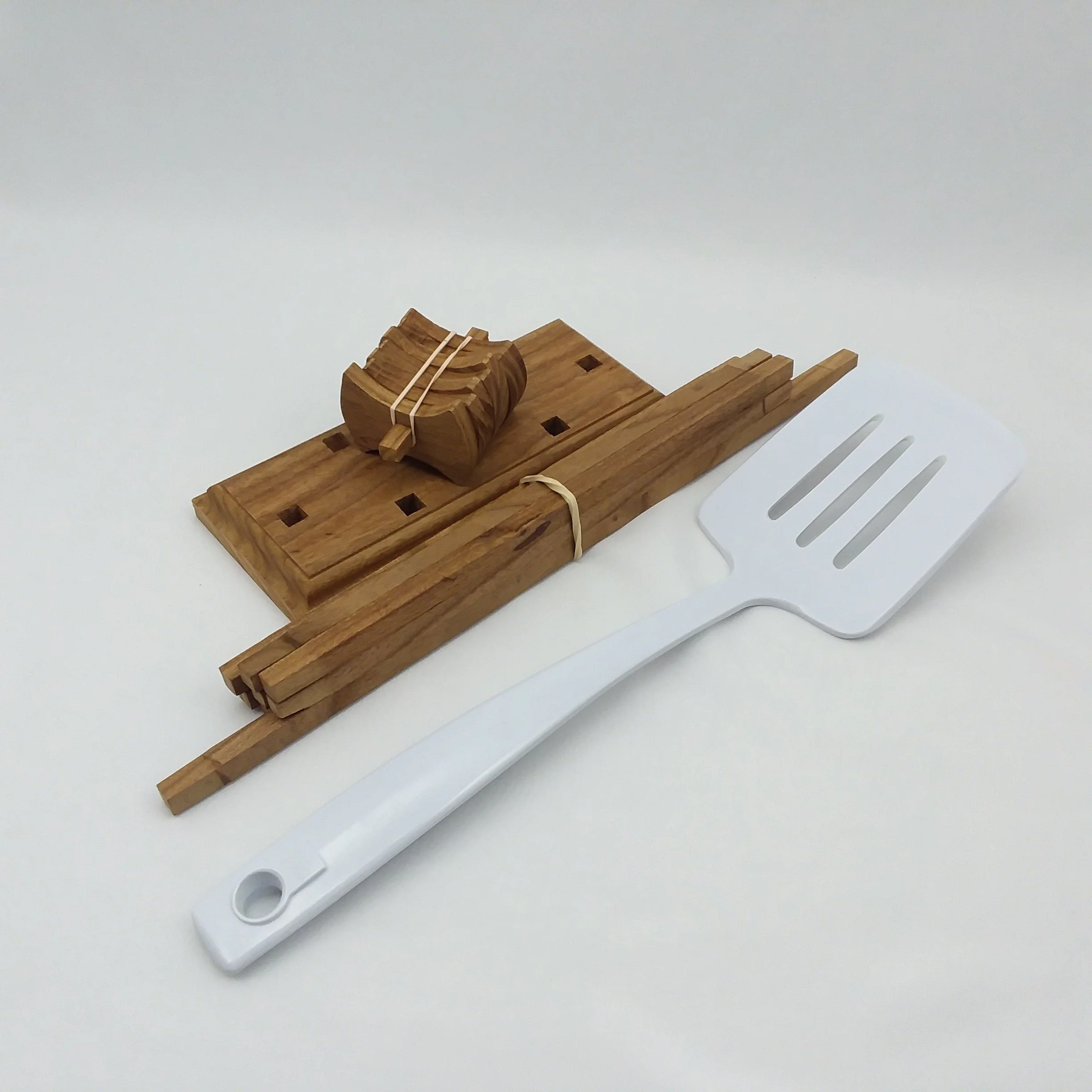 A disassembled wooden drying rack with a spatula of similar size for comparison.