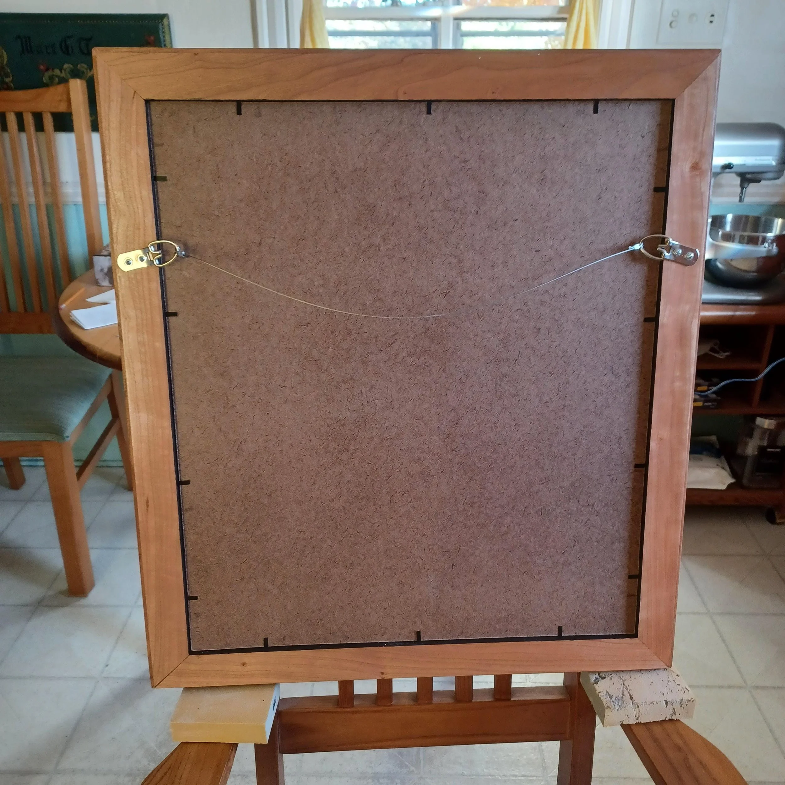 Back of a wooden mirror frame with a wire for hanging.