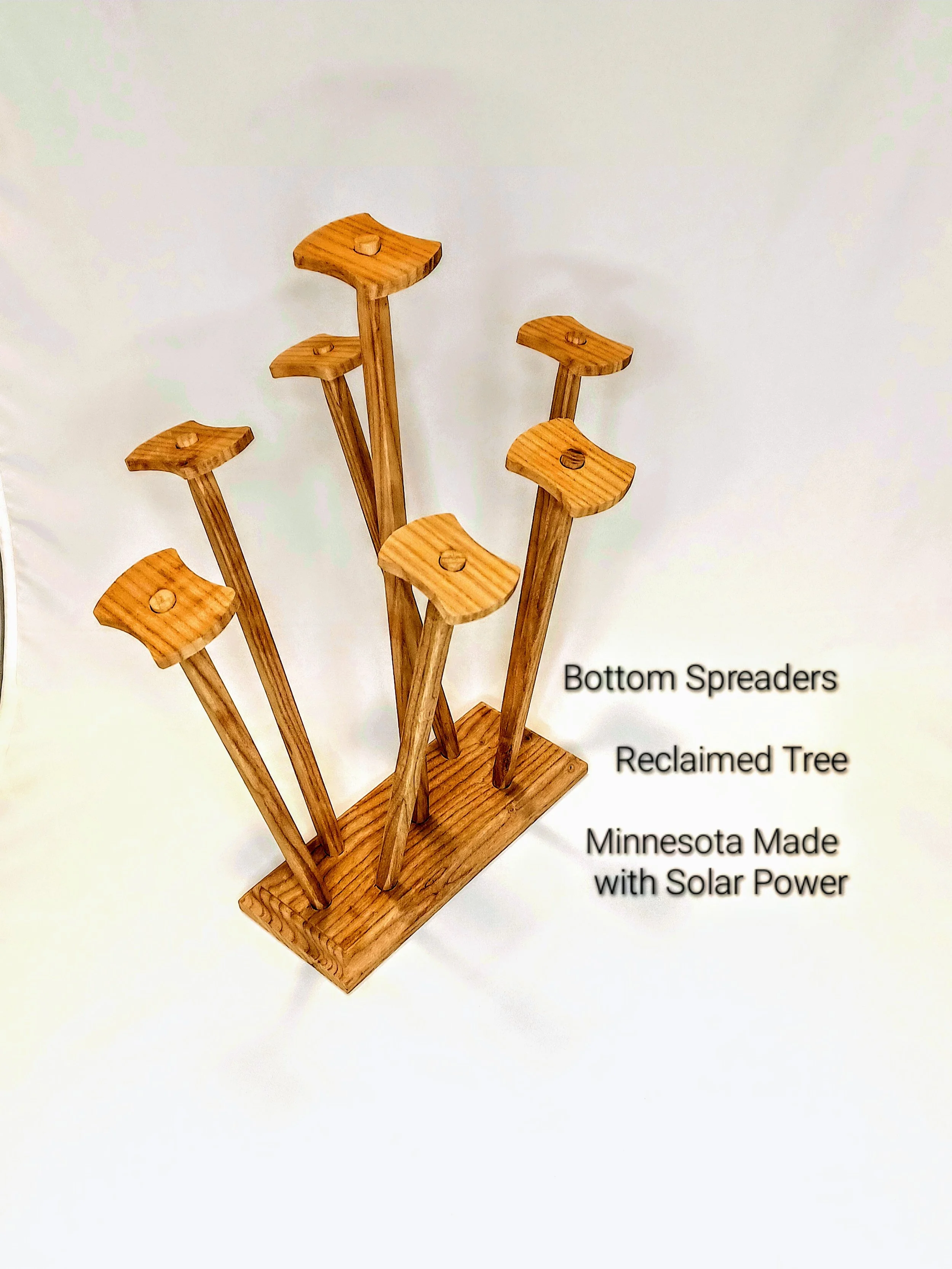 A wooden drying rack with multiple posts that are topped with wood, labeled as 'Bottom Spreaders,' 'Reclaimed Tree,' and 'Minnesota Made with Solar Power'.