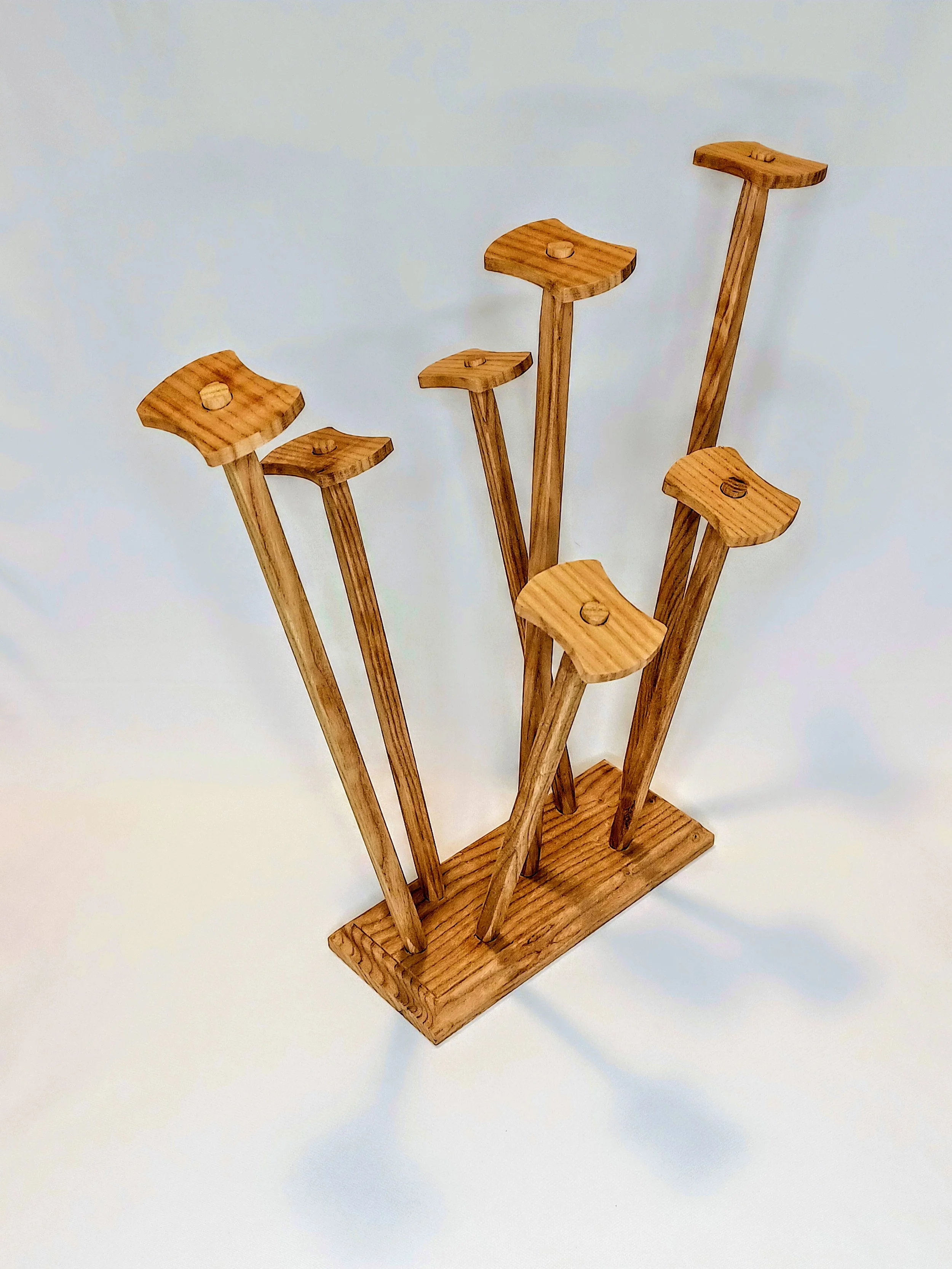 Wooden drying rack with posts of different heights, mounted on a rectangular base for drying plastic baggies.