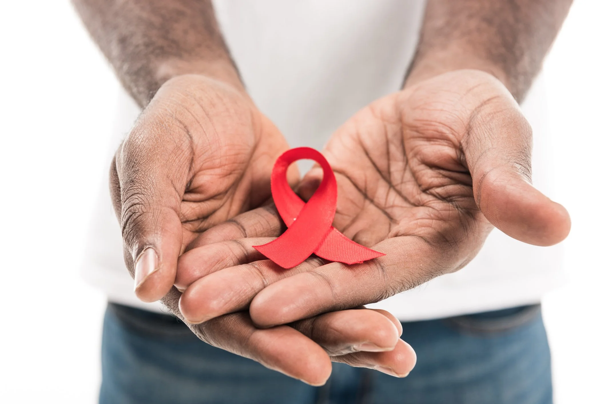 A person's hands holding a red awareness ribbon, symbolizing HIV/AIDS awareness.