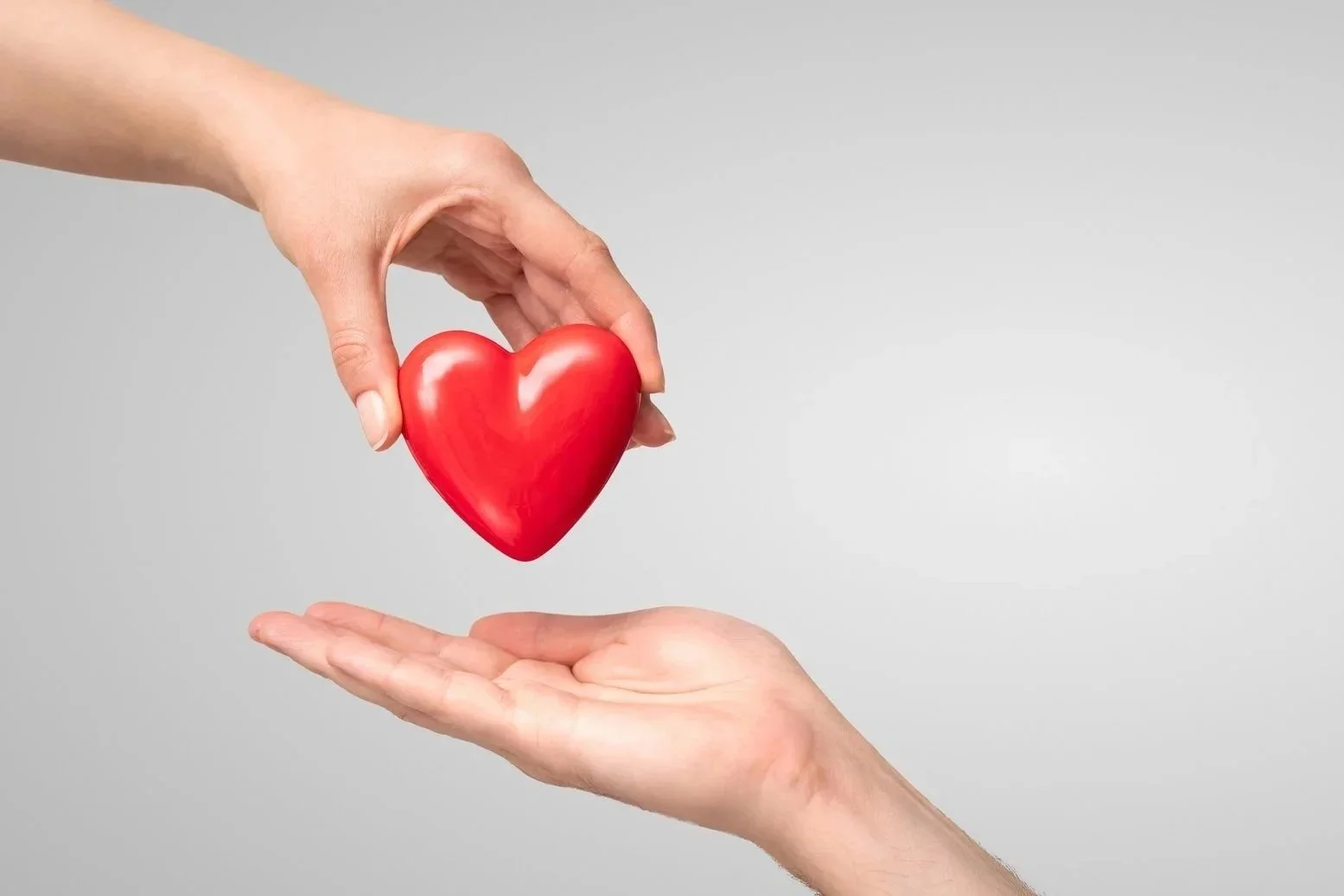 Two hands holding a shiny red heart