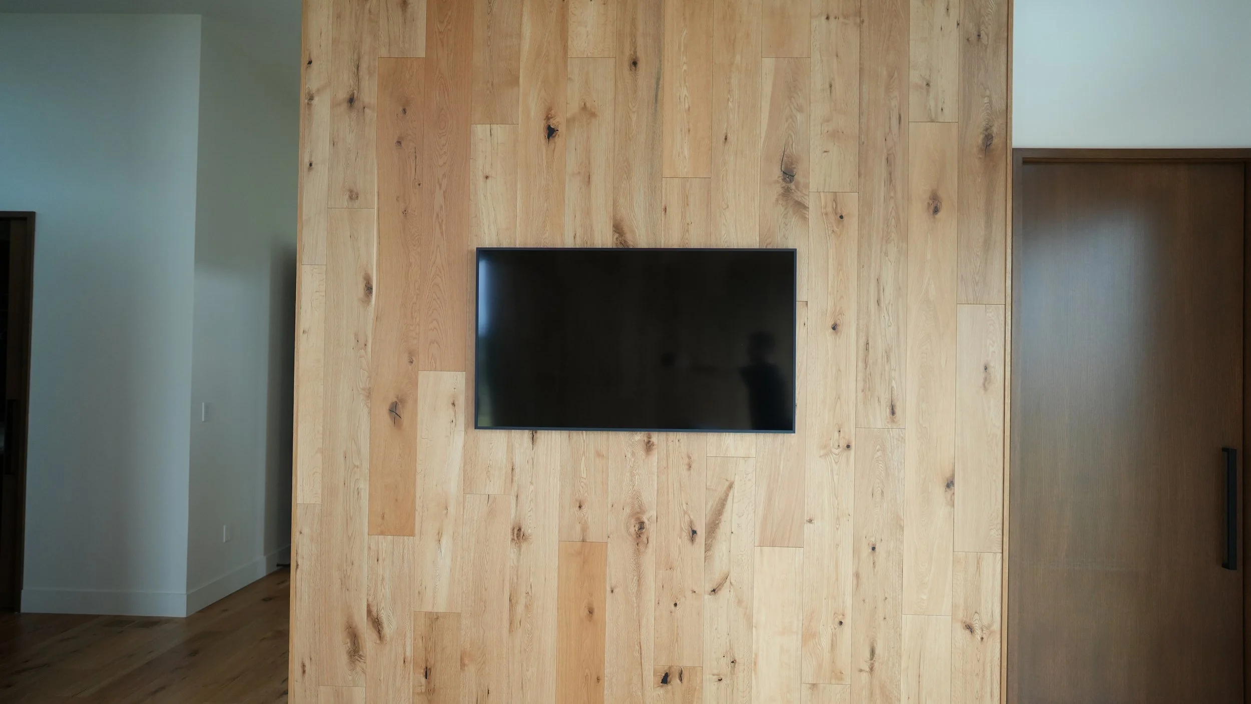 Flat-screen TV mounted on a wooden wall in a modern room.