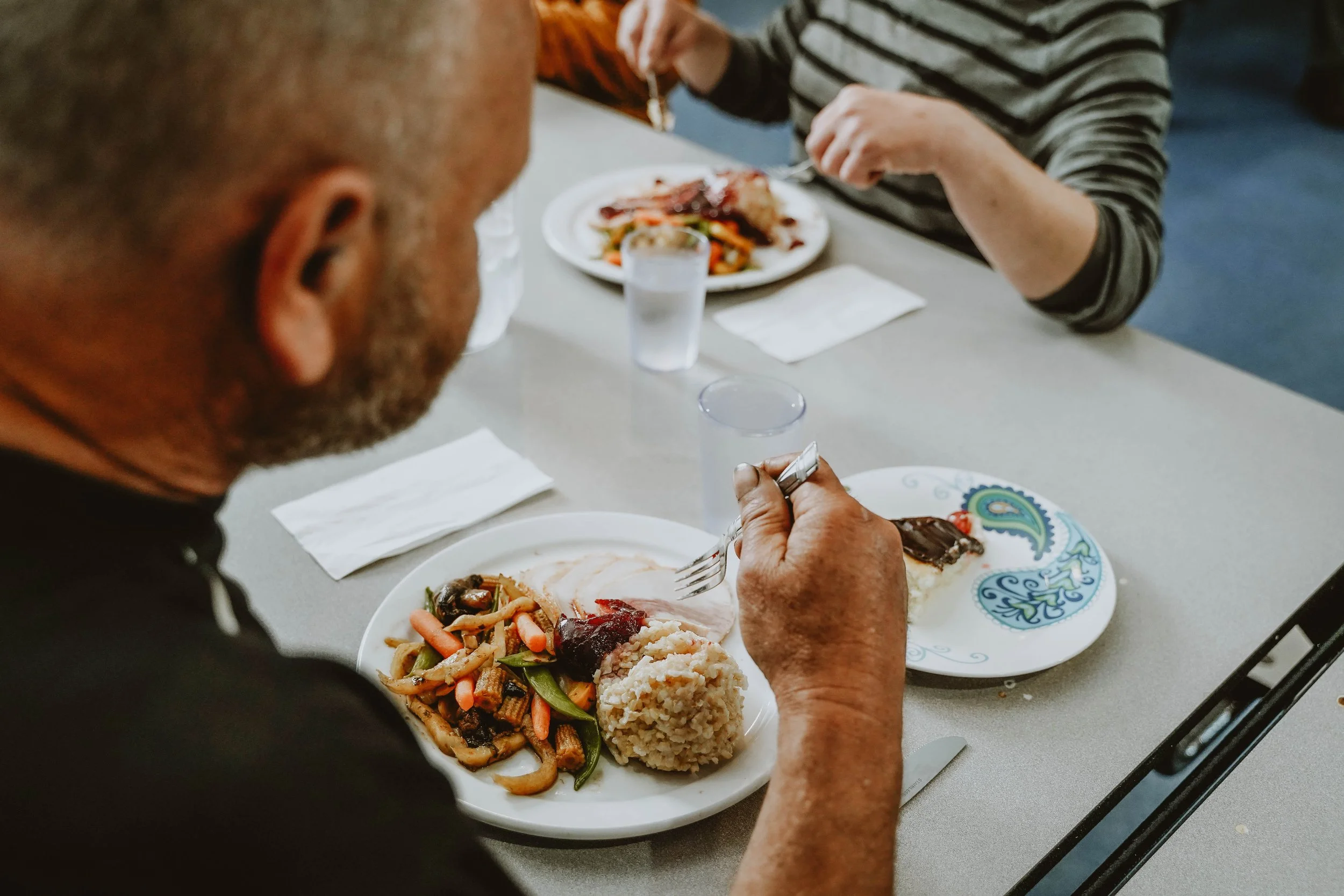 a homeless man eats a meal at a shelter