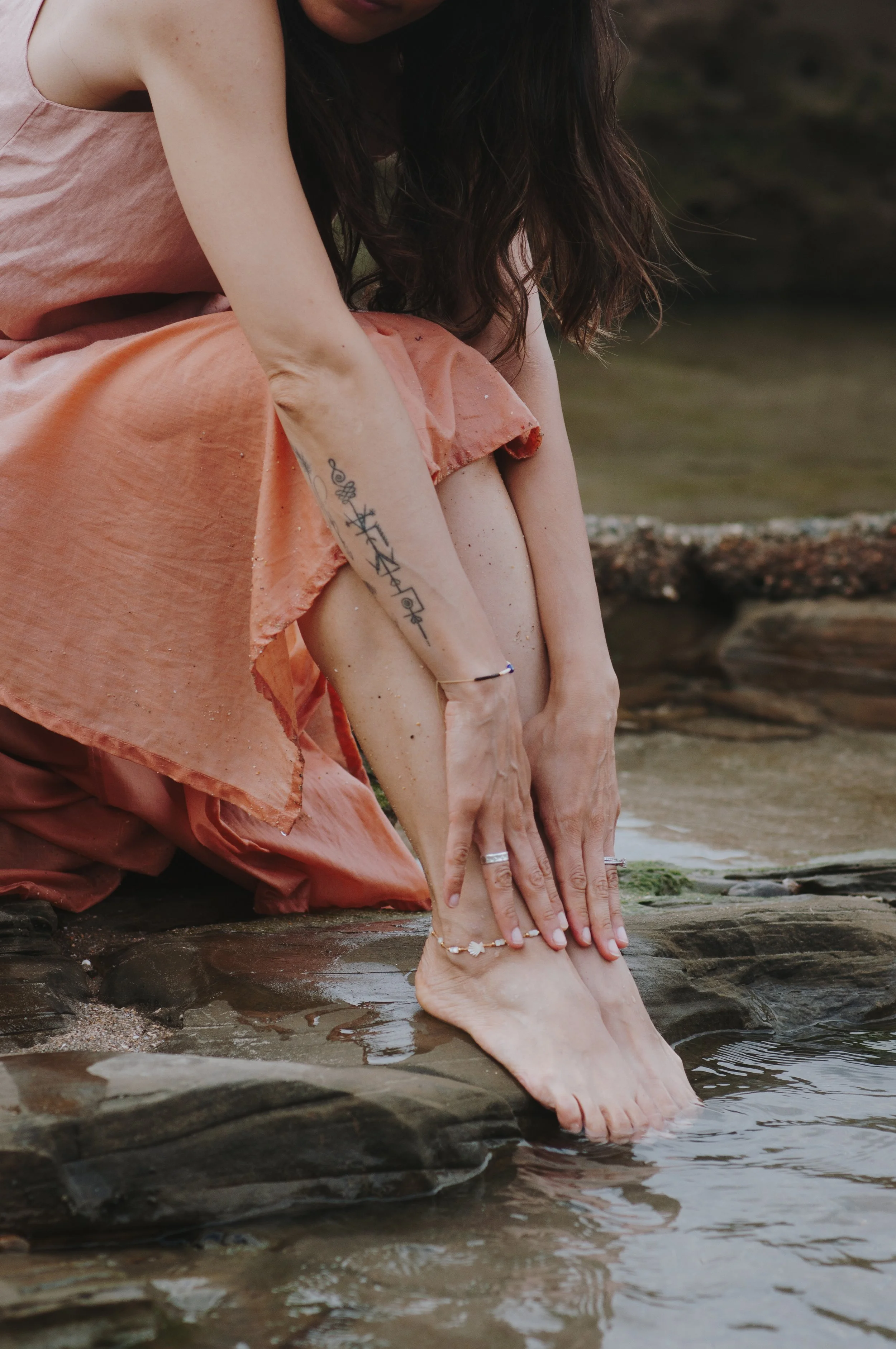 Legs of woman seating on rocks at the beach