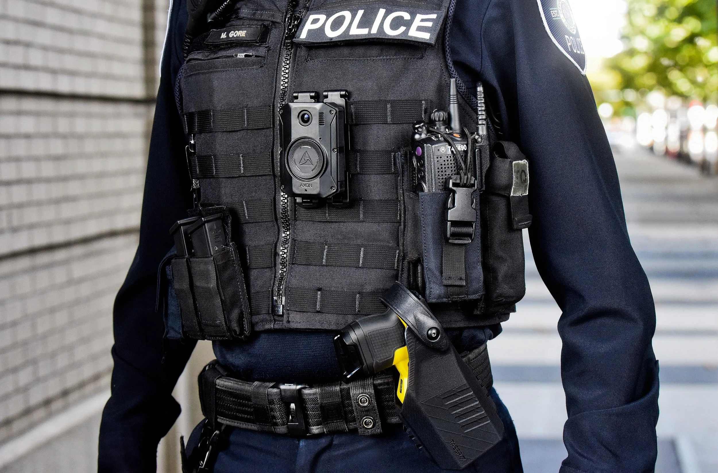 Close-up of police vest showing walkie talkie and body cam strapped on