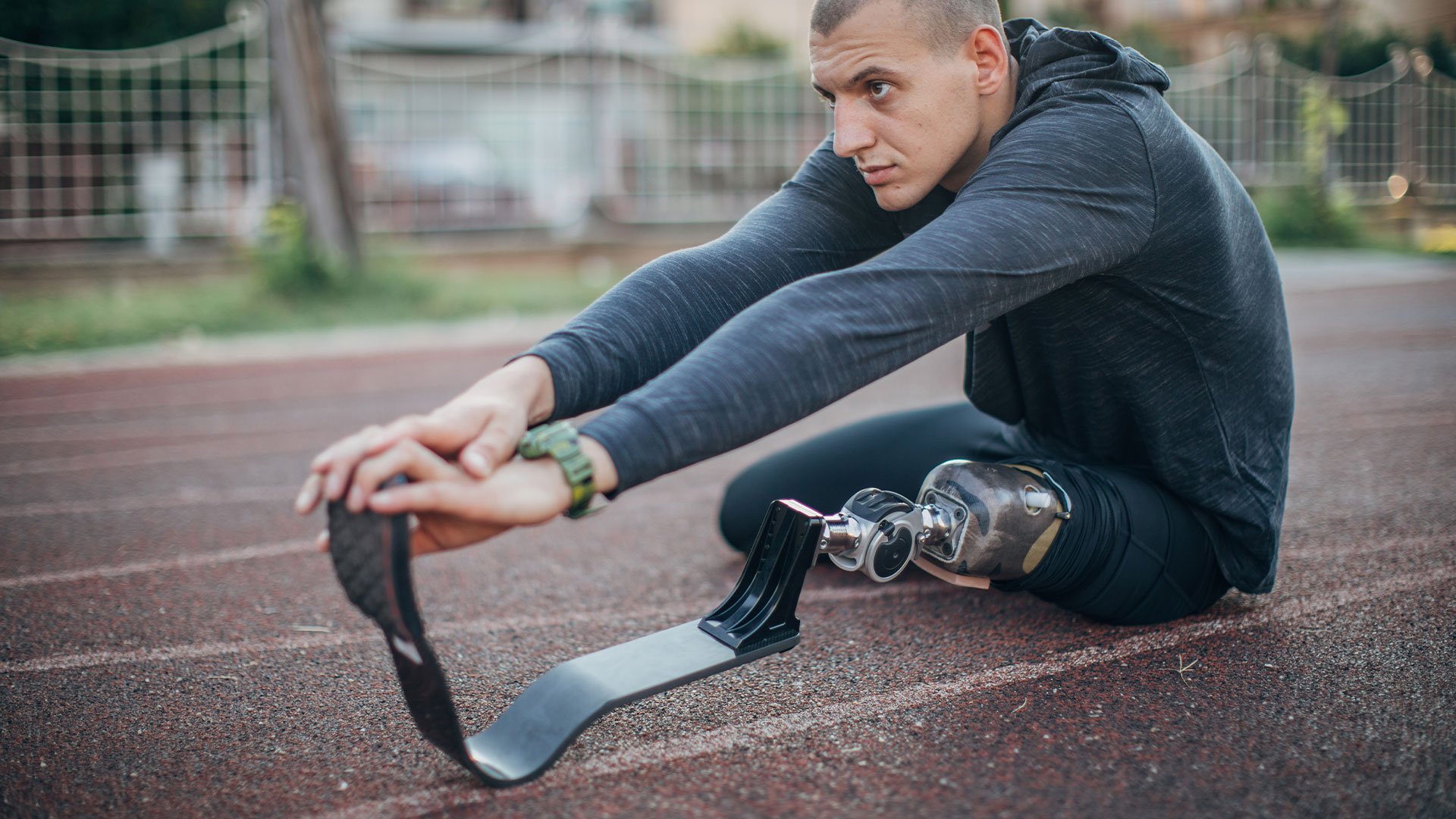 Athlete with prosthetic leg stretching on a track