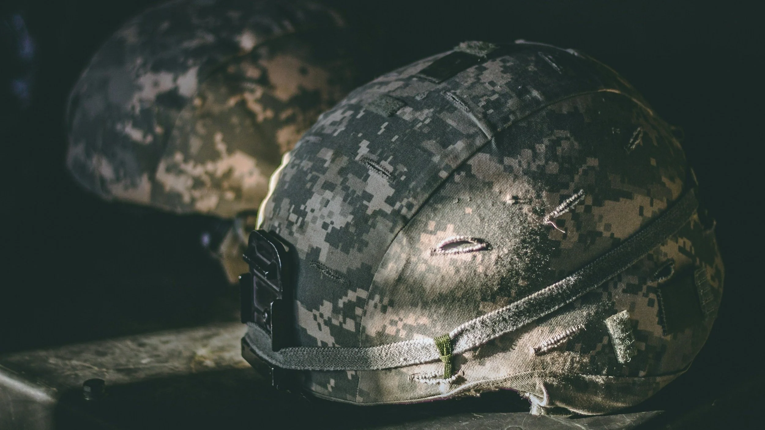 Close-up of worn camouflage military helmets, symbolizing the resilience and service of veterans and first responders.
