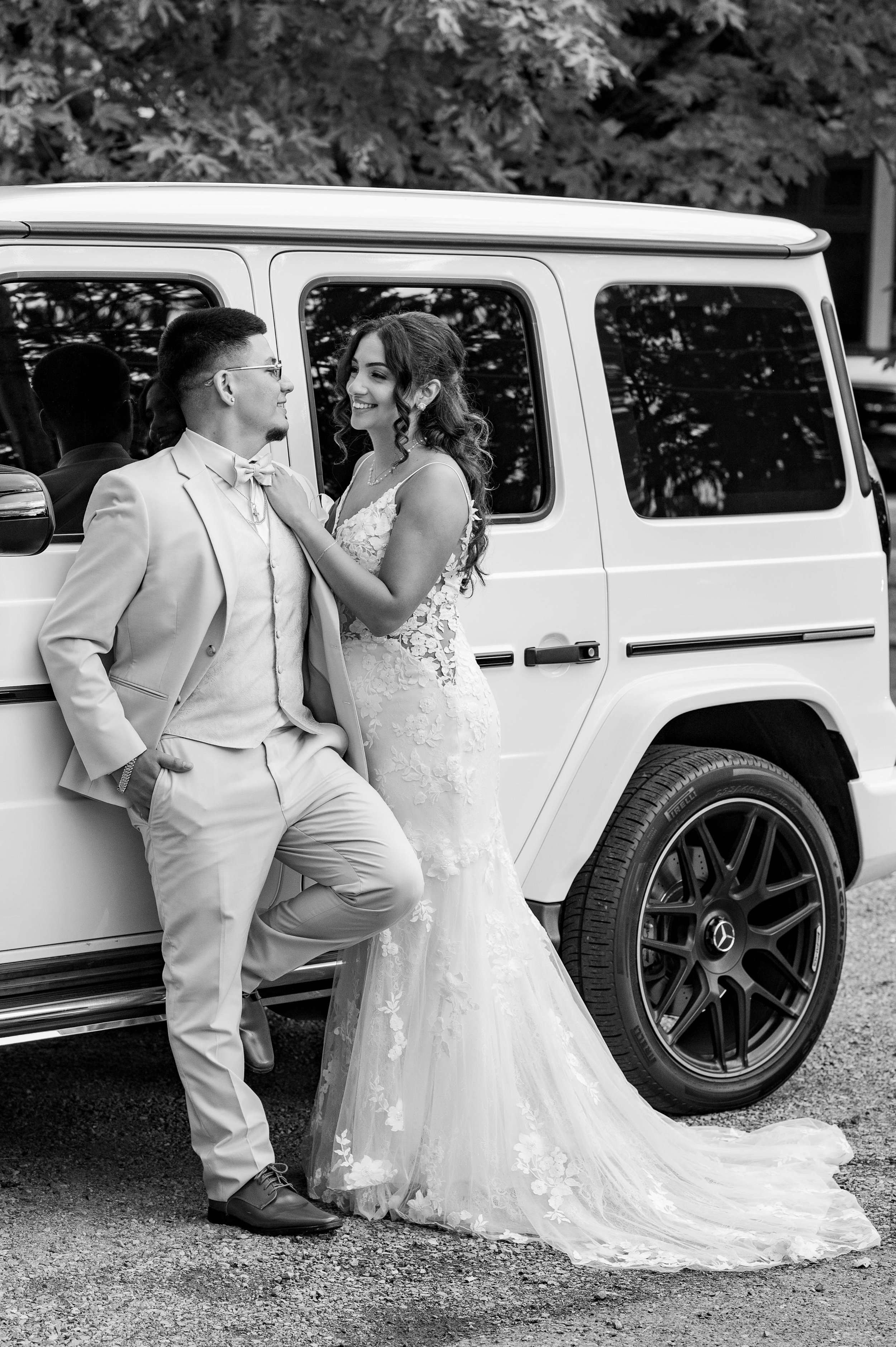 Bride and groom in black and white beside a white SUV, bold documentary wedding photography in Seattle and Tacoma