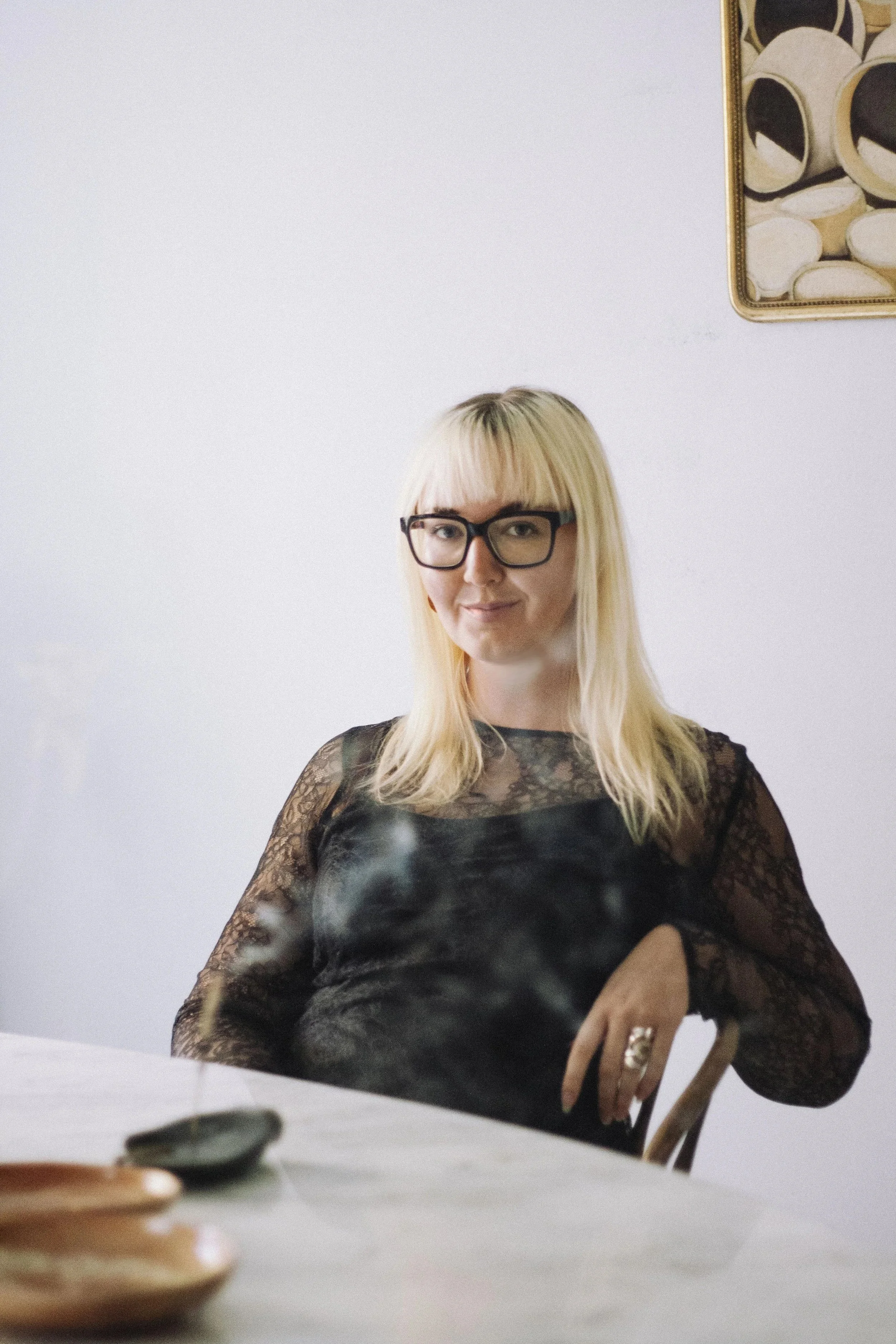 A bleach blong woman wearing glasses smiles at the camera.