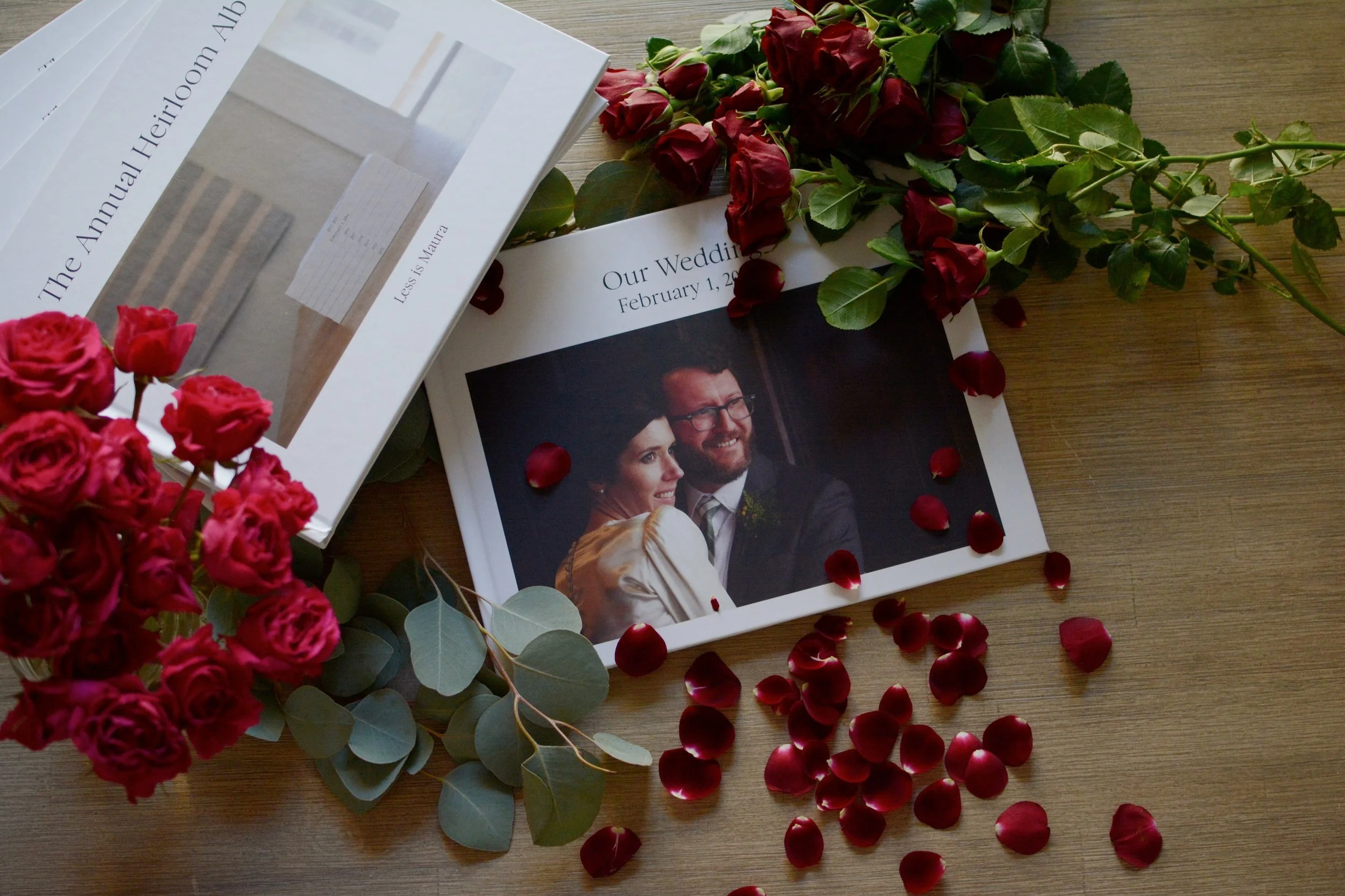 Albums, roses and rose petals lay on a table.